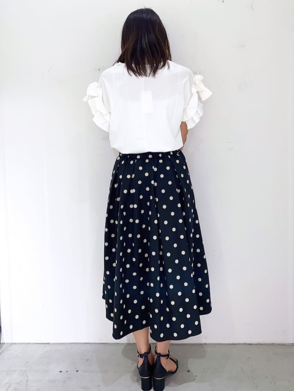 グリーン系のトートバッグ、ブラック系のスカート、ホワイト系のTシャツ/カットソーを着用したレディースの秋コーディネートの3枚目の写真