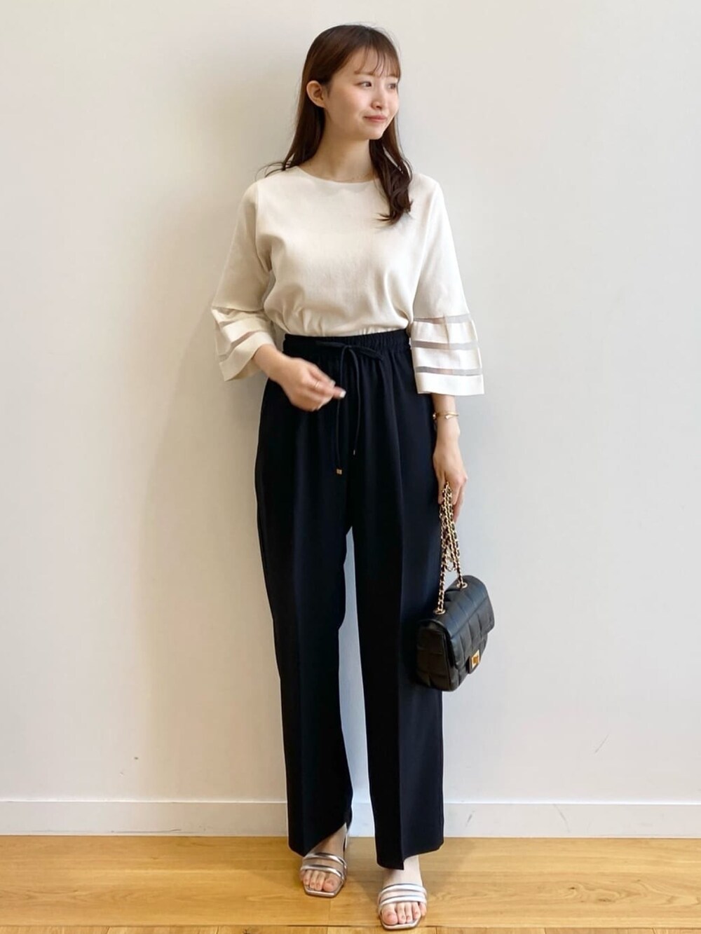 ホワイト系のニット/セーター、ブラック系のその他パンツ、ブラック系のショルダーバッグを着用したレディースの春コーディネートの2枚目の写真