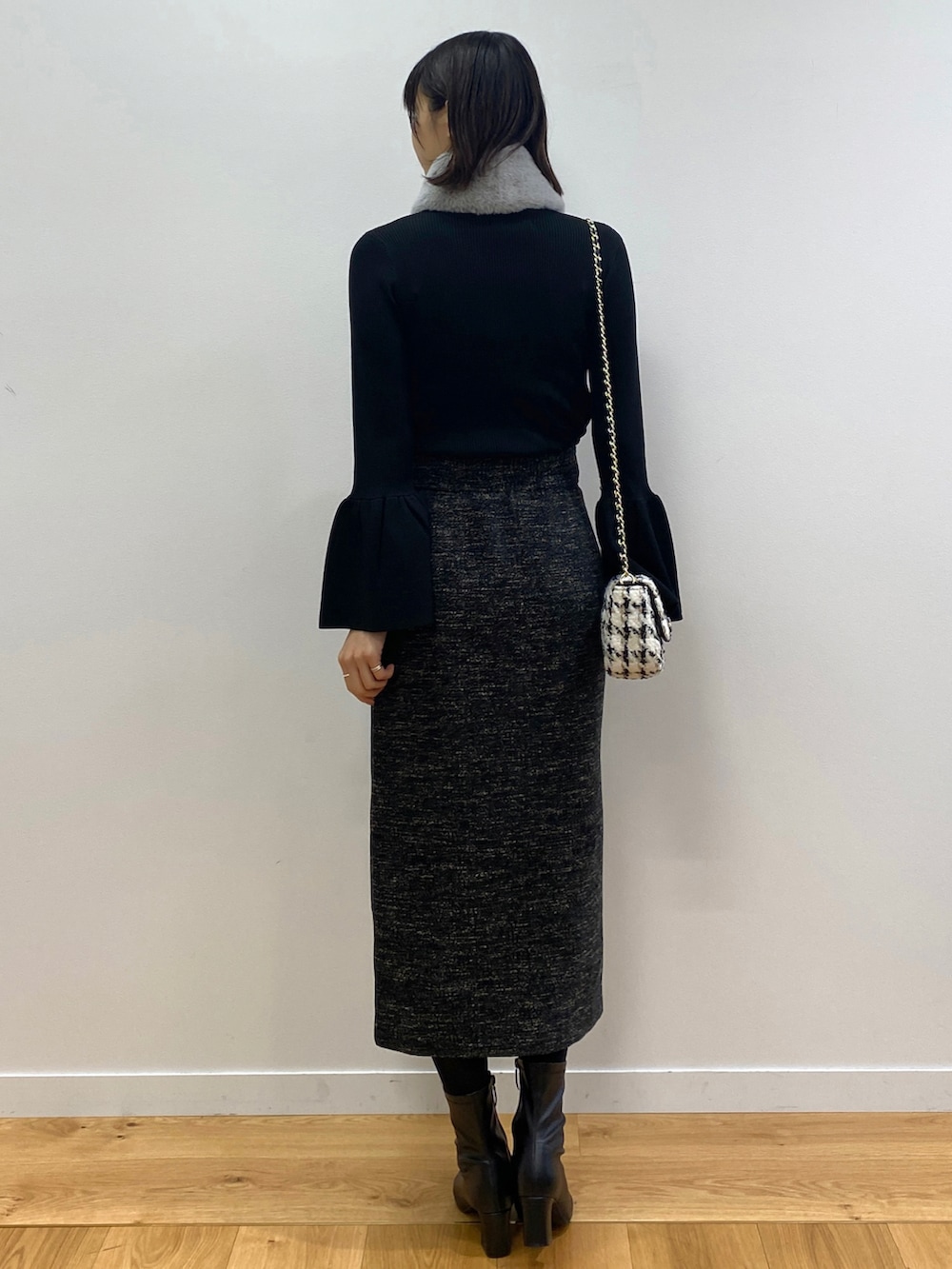 ブラック系のニット/セーター、ブラック系のブーツ、ブラック系のショルダーバッグを着用したレディースの冬コーディネートの3枚目の写真