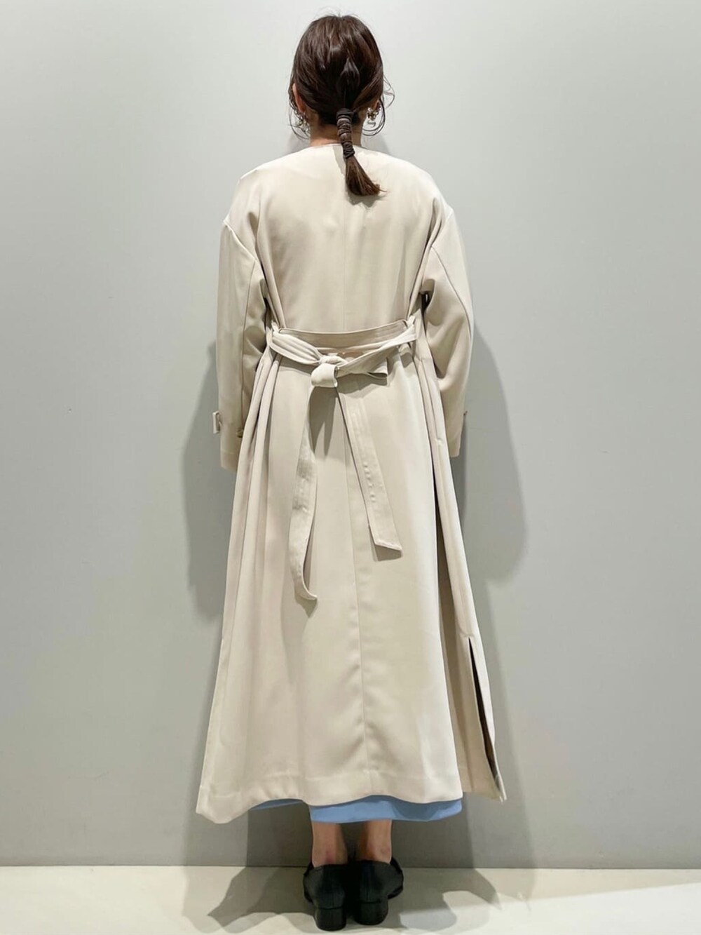 ベージュ系のステンカラーコート、ホワイト系のニット/セーター、ブルー系のスカートを着用したレディースの春コーディネートの3枚目の写真