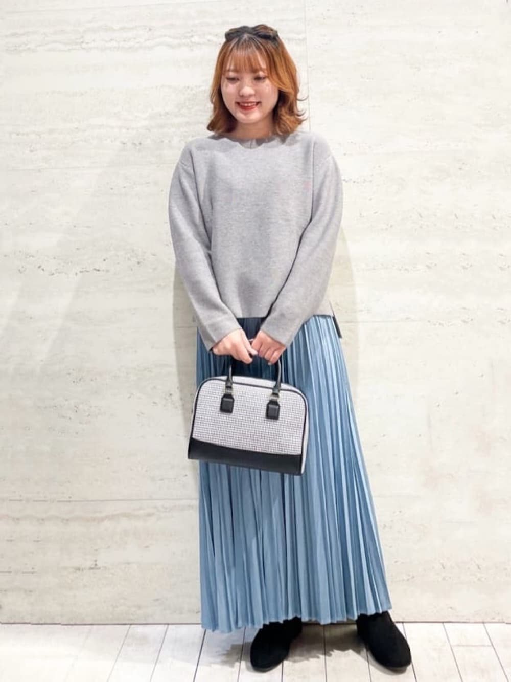 ブルー系のスカート、グレー系のニット/セーター、ブラック系のダウンジャケット/コートを着用したレディースの秋コーディネートの2枚目の写真