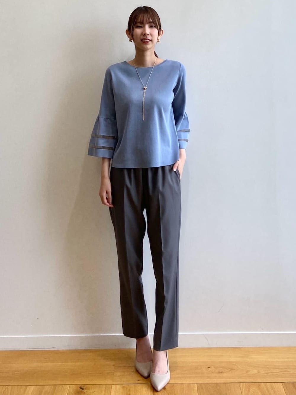 グレー系のその他パンツ、ベージュ系のパンプス、ブルー系のニット/セーターを着用したレディースの秋コーディネートの2枚目の写真