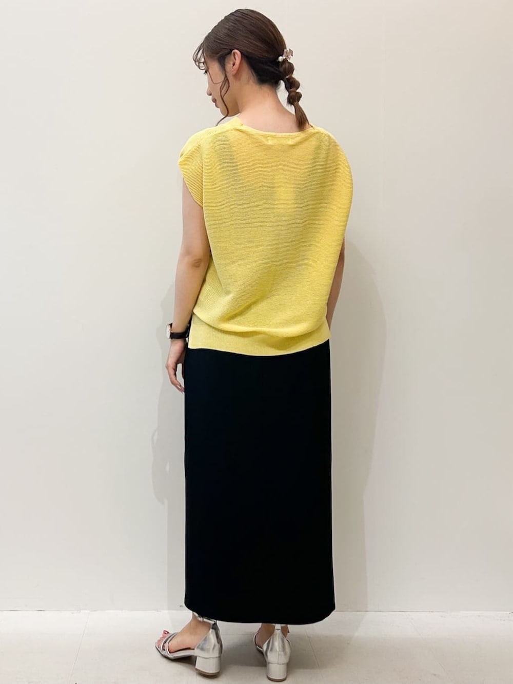 ブラック系のスカート、シルバー系のサンダル、イエロー系のニット/セーターを着用したレディースの夏コーディネートの3枚目の写真