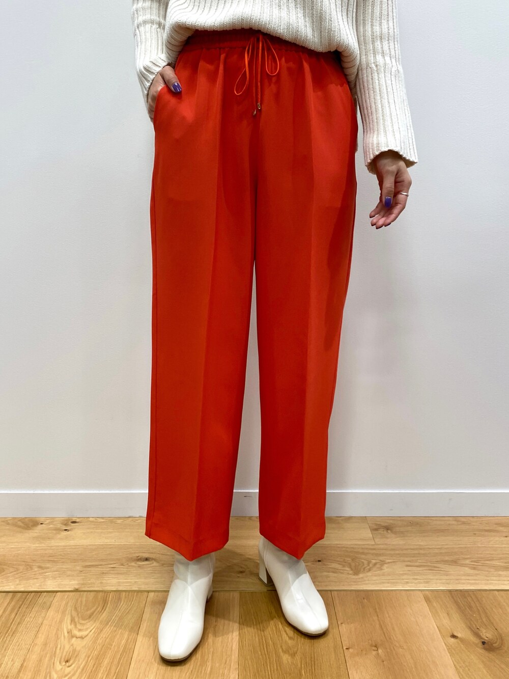 グリーン系のニット/セーター、ベージュ系のノーカラーコート、オレンジ系のその他パンツを着用したレディースの秋コーディネートの5枚目の写真