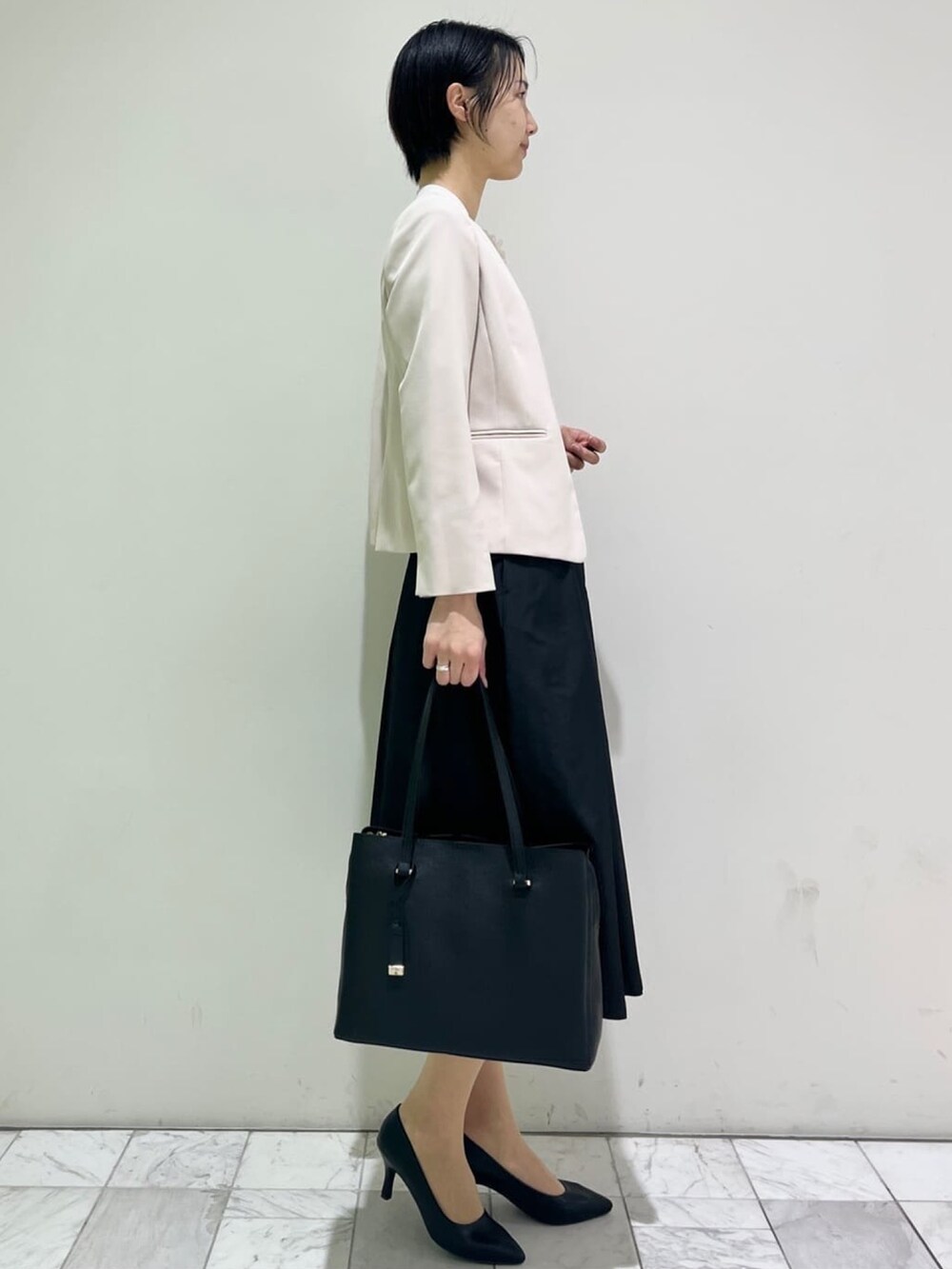 ベージュ系のノーカラージャケット、ブラック系のスカート、ブラック系のパンプスを着用したレディースの冬コーディネートの4枚目の写真