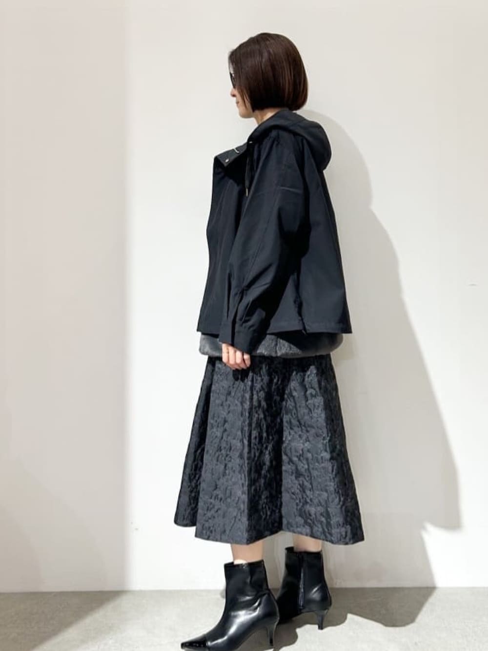 ブラック系のブルゾン、グリーン系のニット/セーター、ブラック系のスカートを着用したレディースの秋コーディネートの2枚目の写真