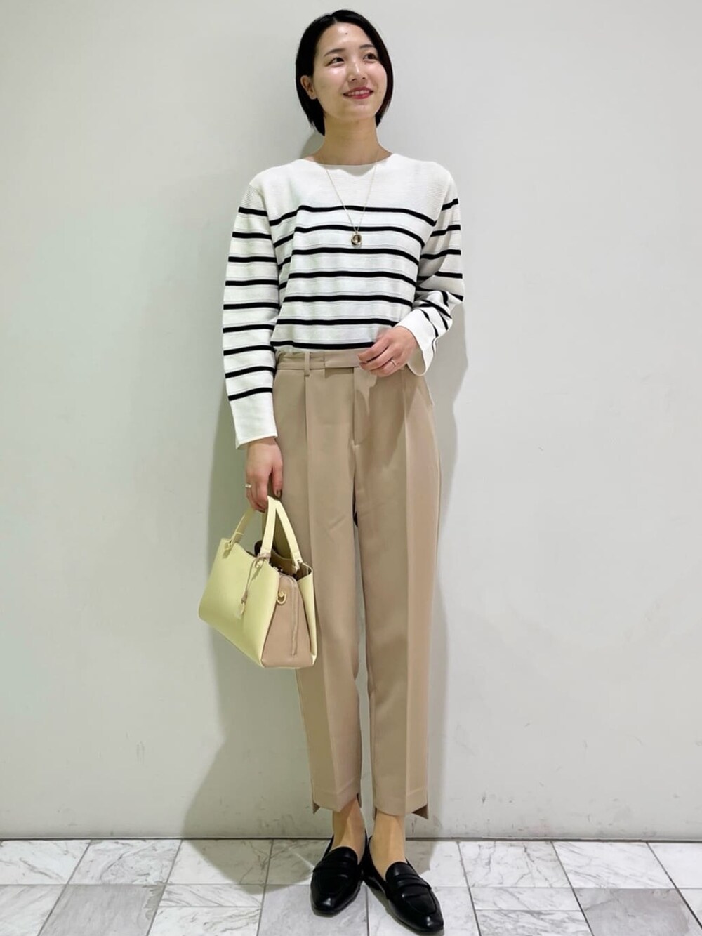 ベージュ系のその他パンツ、ゴールド系のその他シューズ、ホワイト系のニット/セーターを着用したレディースの春コーディネートの4枚目の写真