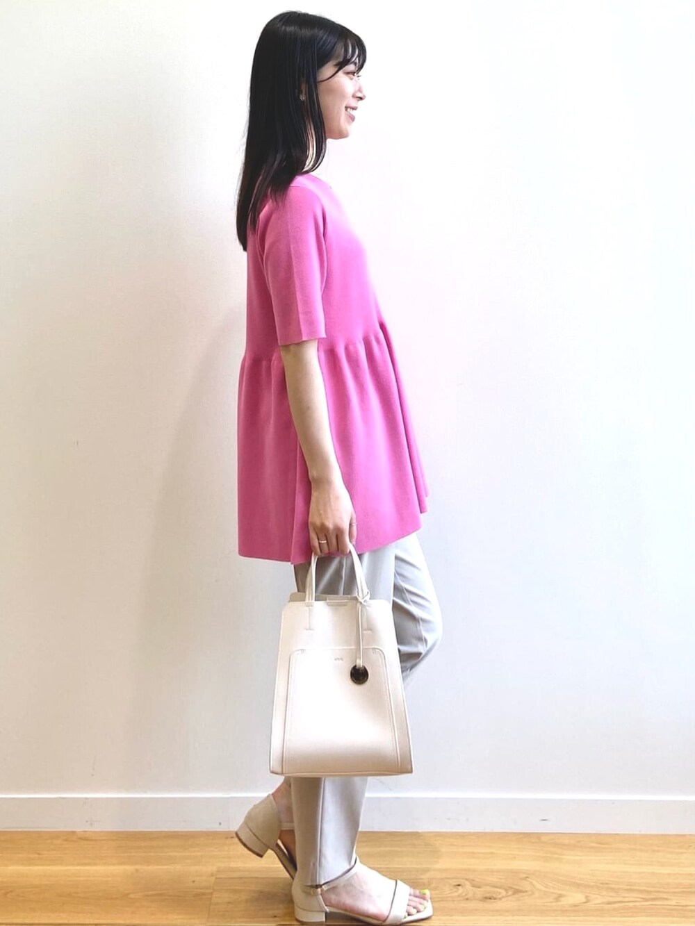 ピンク系のニット/セーター、ベージュ系のその他パンツ、ホワイト系のトートバッグを着用したレディースの夏コーディネートの2枚目の写真