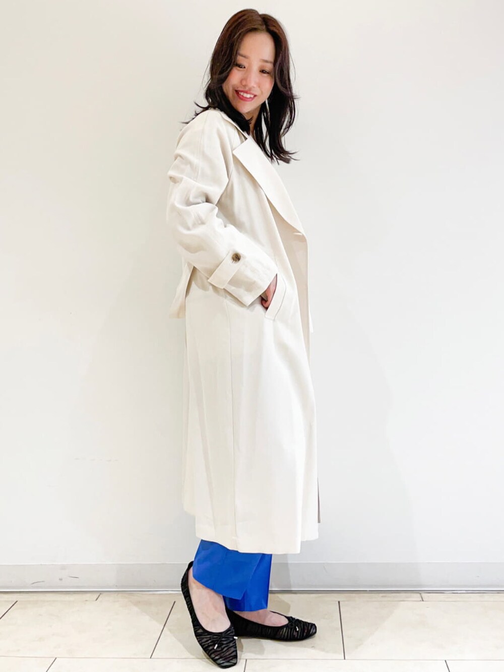 ホワイト系のトレンチコート、ホワイト系のニット/セーター、ブラック系のショルダーバッグを着用したレディースの春コーディネートの2枚目の写真