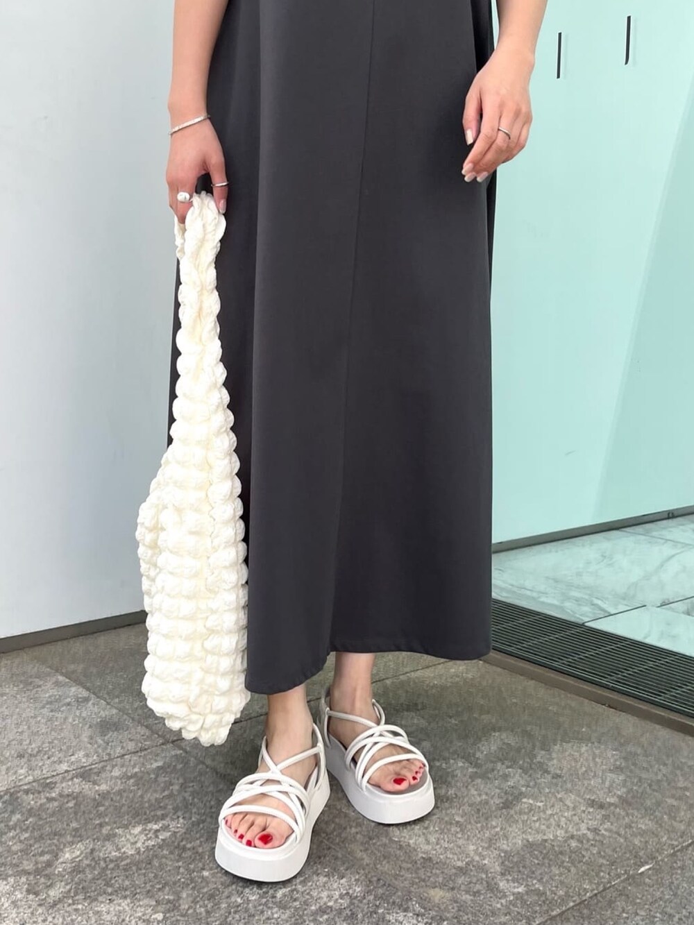 グレー系のワンピース、ホワイト系のサンダル、ホワイト系のショルダーバッグを着用したレディースの春コーディネートの3枚目の写真