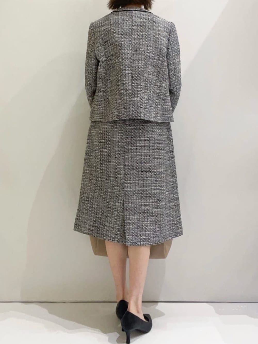 ブラック系のスカート、ブラック系のパンプス、ベージュ系のトートバッグを着用したレディースの冬コーディネートの3枚目の写真