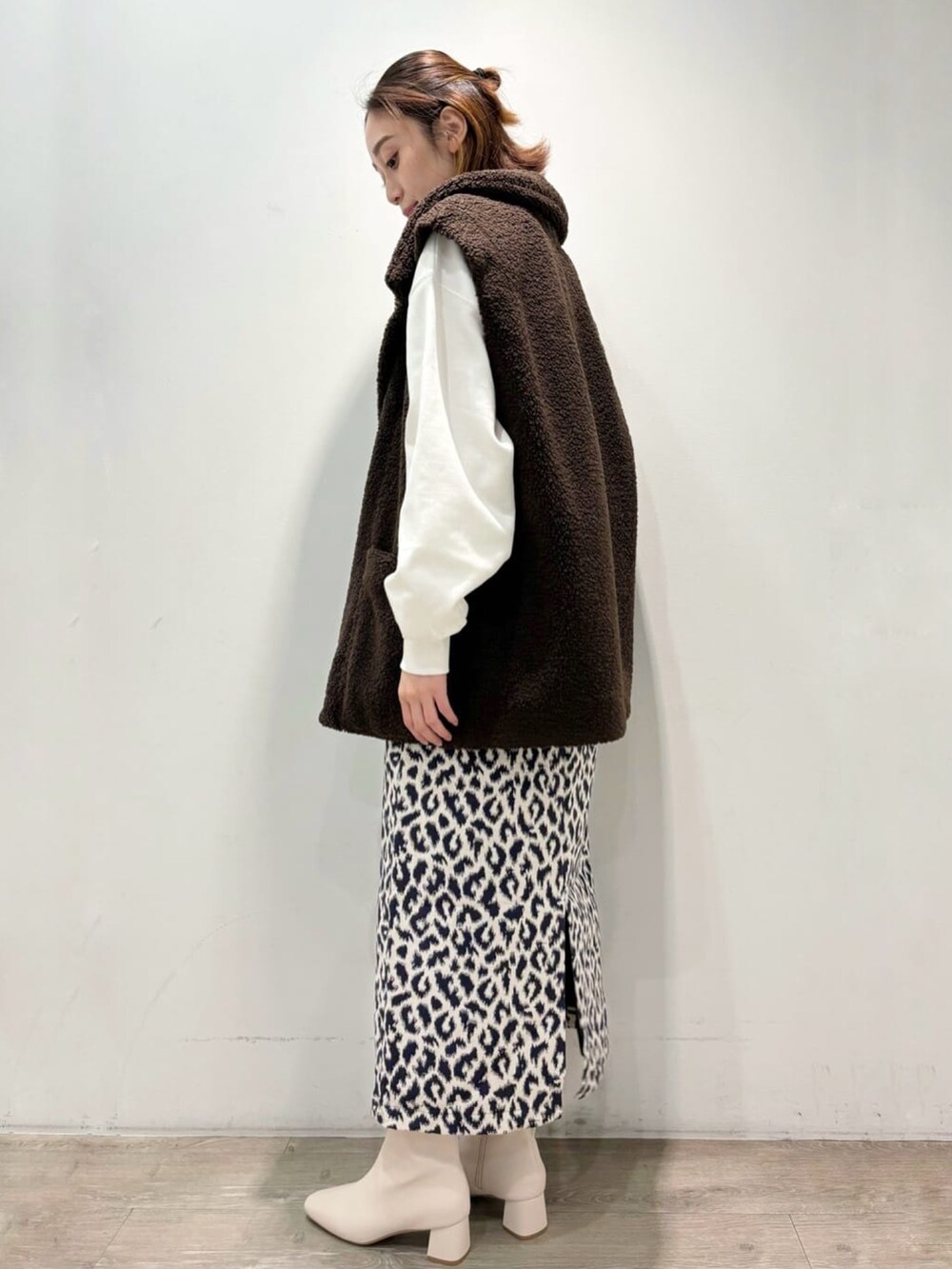 ブルー系のスカート、ブラウン系のベスト、ホワイト系のTシャツ/カットソーを着用したレディースの秋コーディネートの3枚目の写真