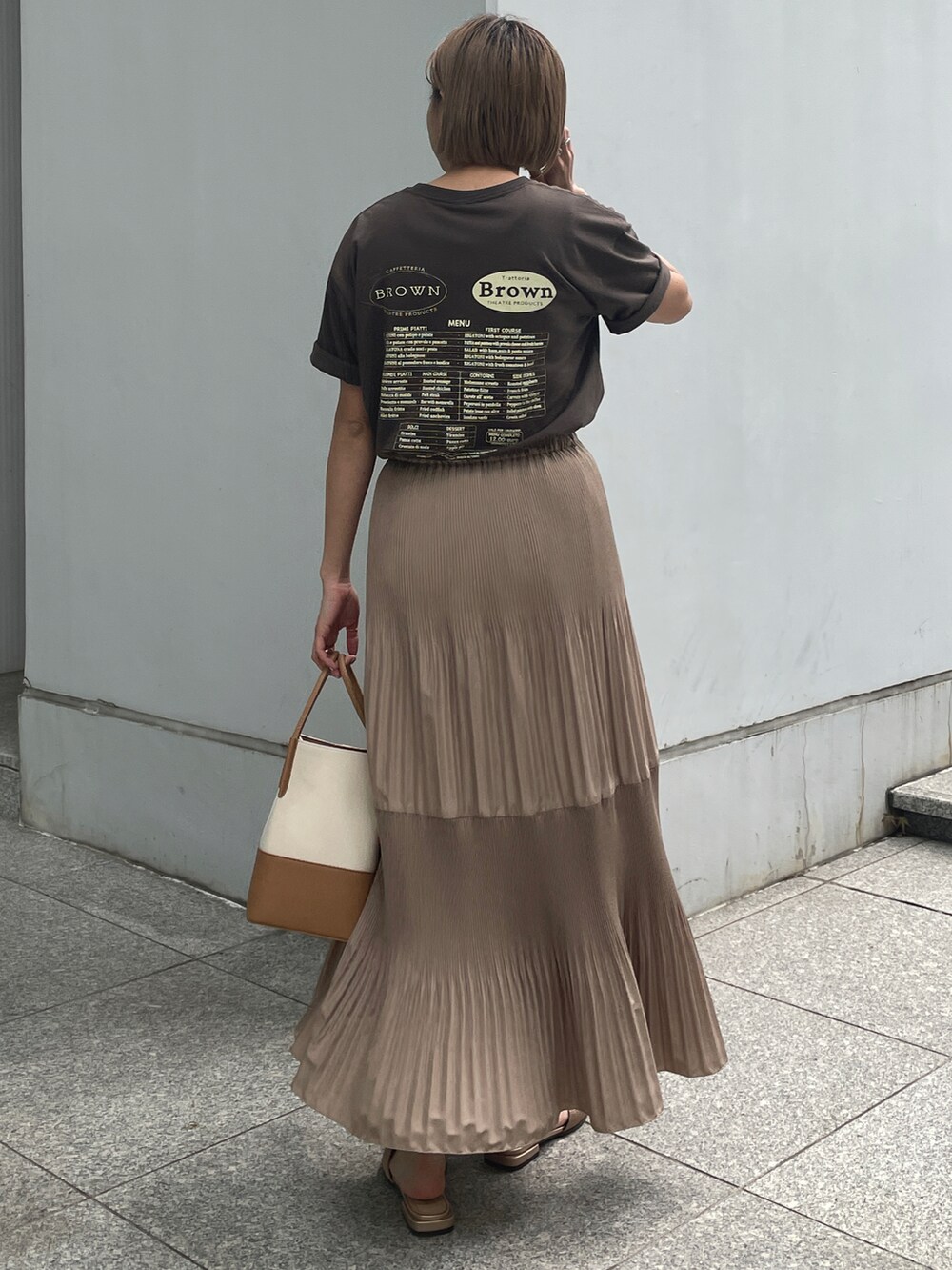 ブラウン系のTシャツ/カットソー、イエロー系のスカート、イエロー系のトートバッグを着用したレディースの春コーディネートの2枚目の写真