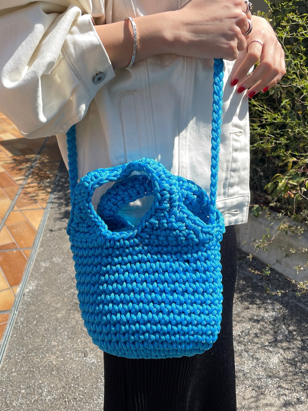 ホワイト系のデニムジャケット、ブルー系のショルダーバッグ、ブラック系のワンピースを着用したレディースの春コーディネートの3枚目の写真