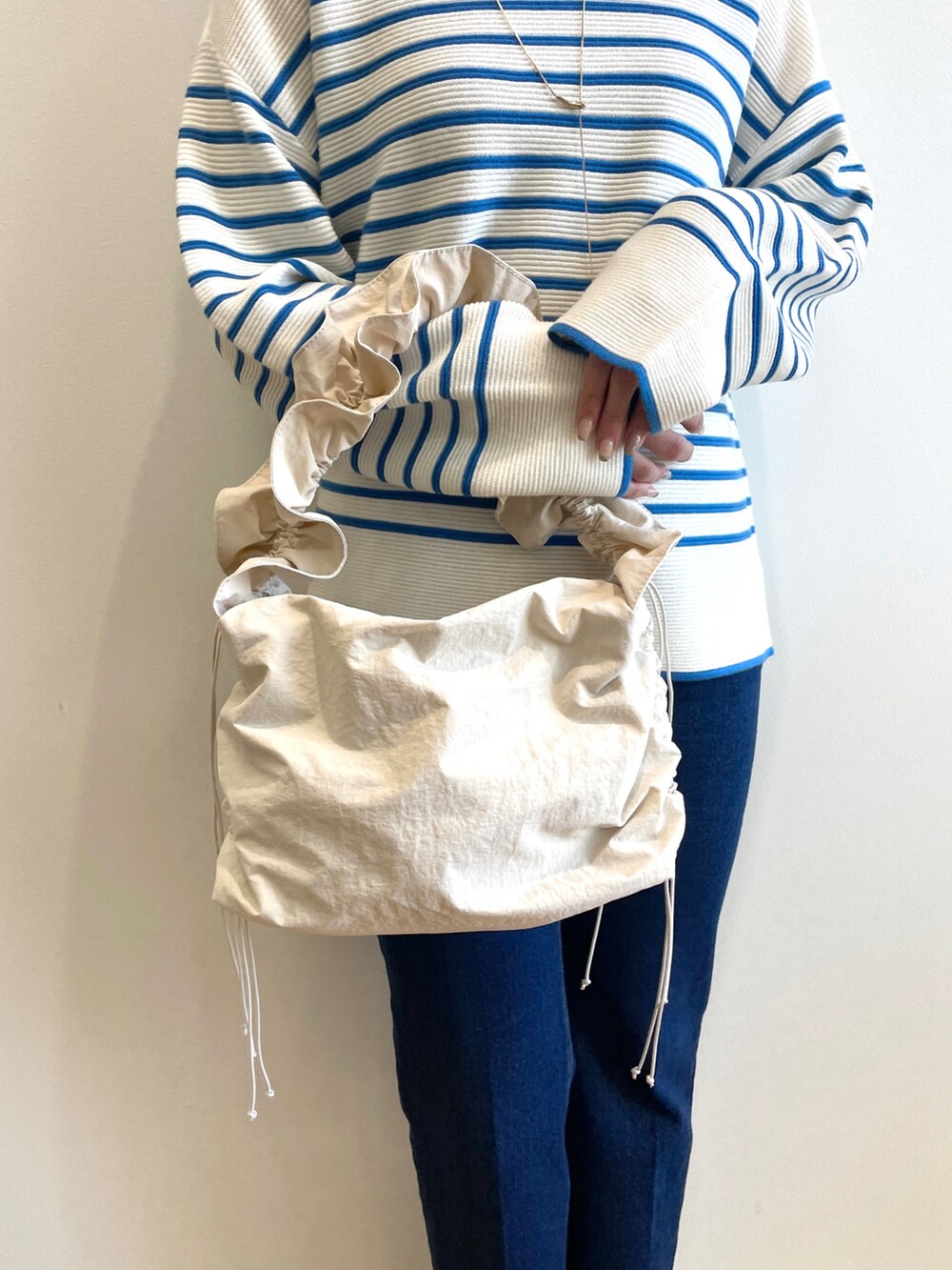 ブルー系のニット/セーター、ブルー系のデニムパンツ、ホワイト系のブーツを着用したレディースの冬コーディネートの5枚目の写真