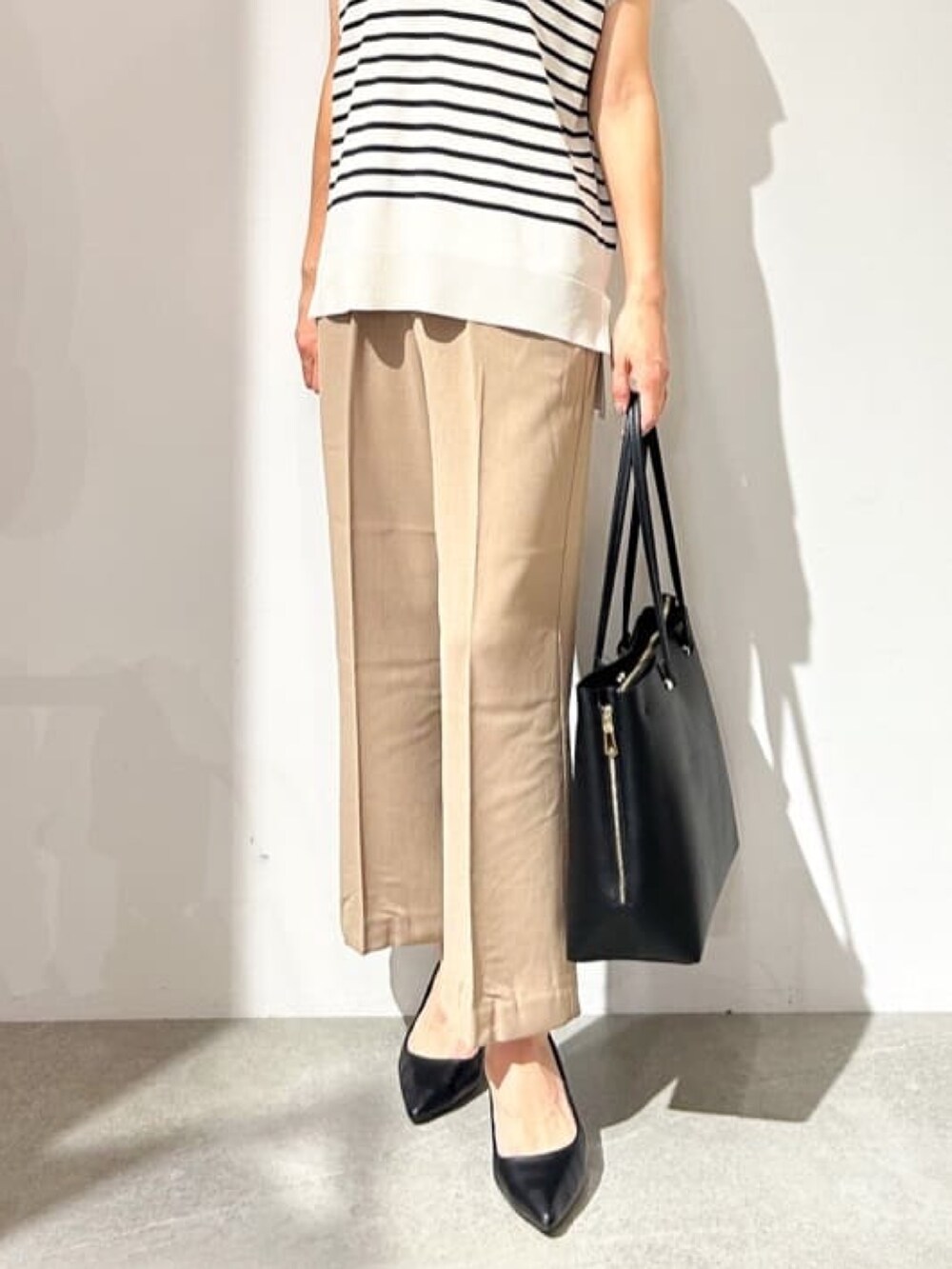 ベージュ系のニット/セーター、イエロー系のその他パンツ、ブラック系のパンプスを着用したレディースの夏コーディネートの4枚目の写真