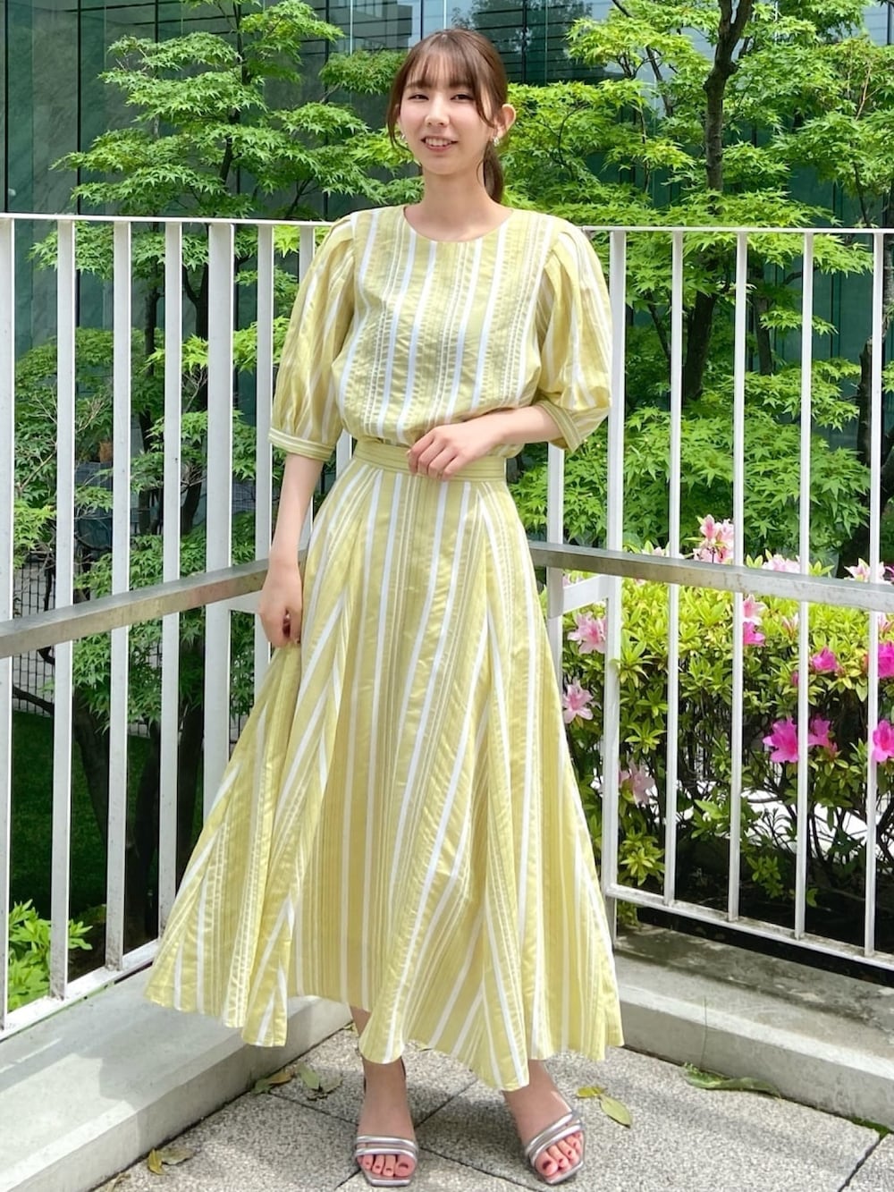 イエロー系のシャツ/ブラウス、イエロー系のスカート、シルバー系のサンダルを着用したレディースの春コーディネートの3枚目の写真
