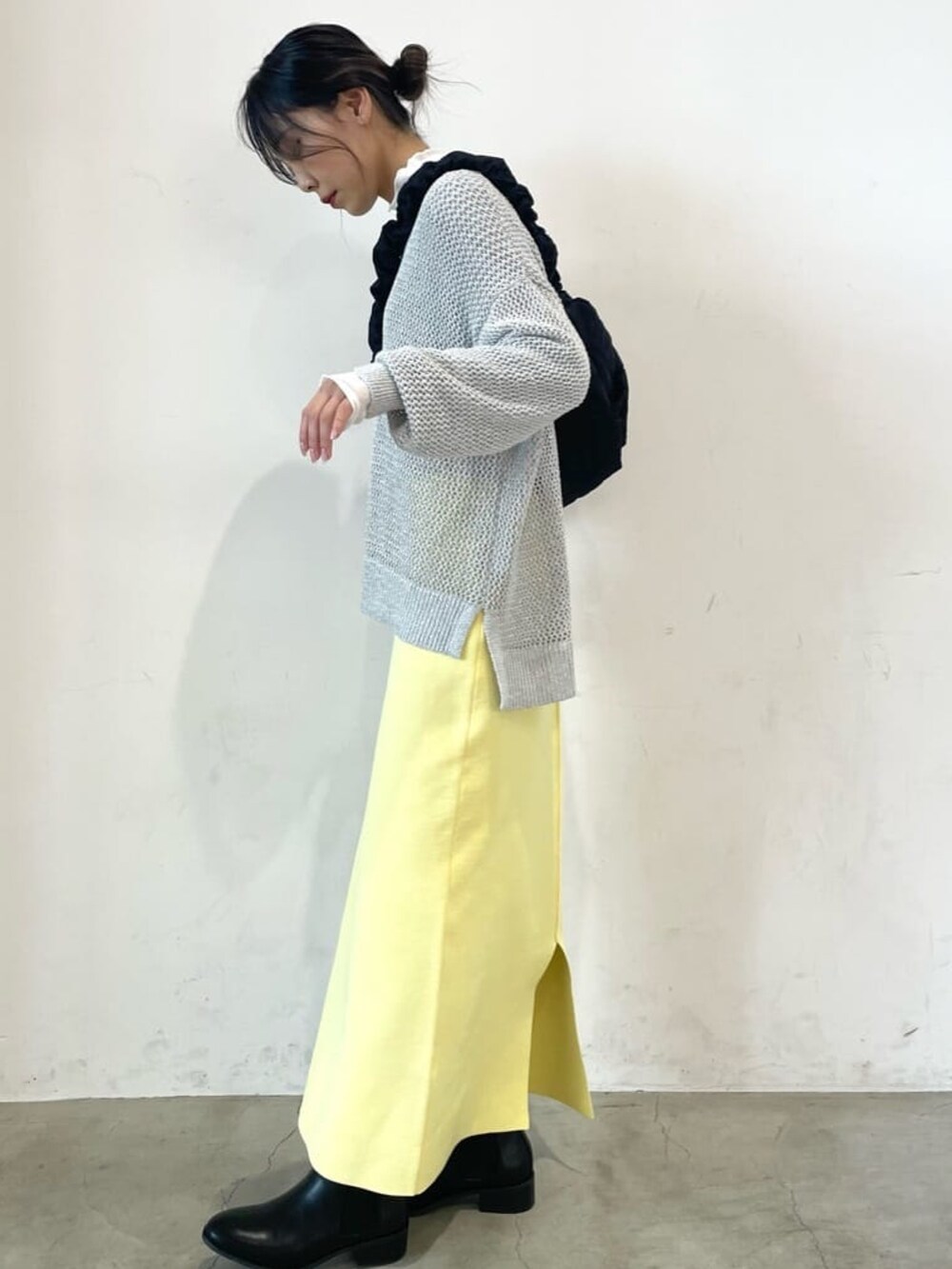 ホワイト系のニット/セーター、ホワイト系のTシャツ/カットソー、イエロー系のスカートを着用したレディースの冬コーディネートの2枚目の写真