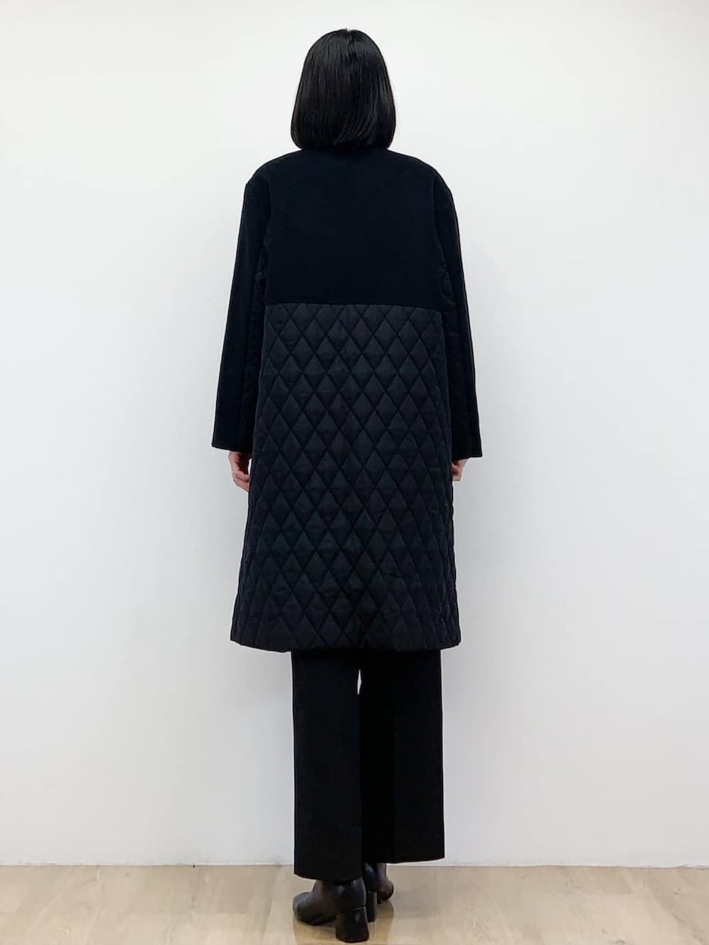 ブラック系のノーカラーコート、ベージュ系のニット/セーター、ブラック系のその他パンツを着用したレディースの秋コーディネートの4枚目の写真