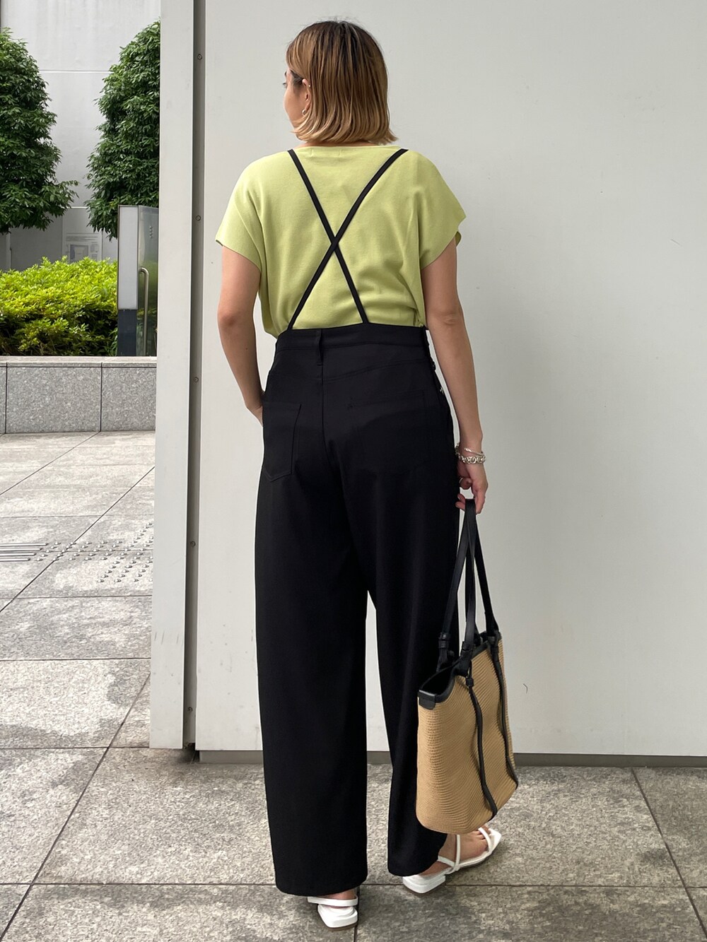 グリーン系のニット/セーター、ブラック系のサロペット/オーバーオール、ブラック系のトートバッグを着用したレディースの夏コーディネートの2枚目の写真