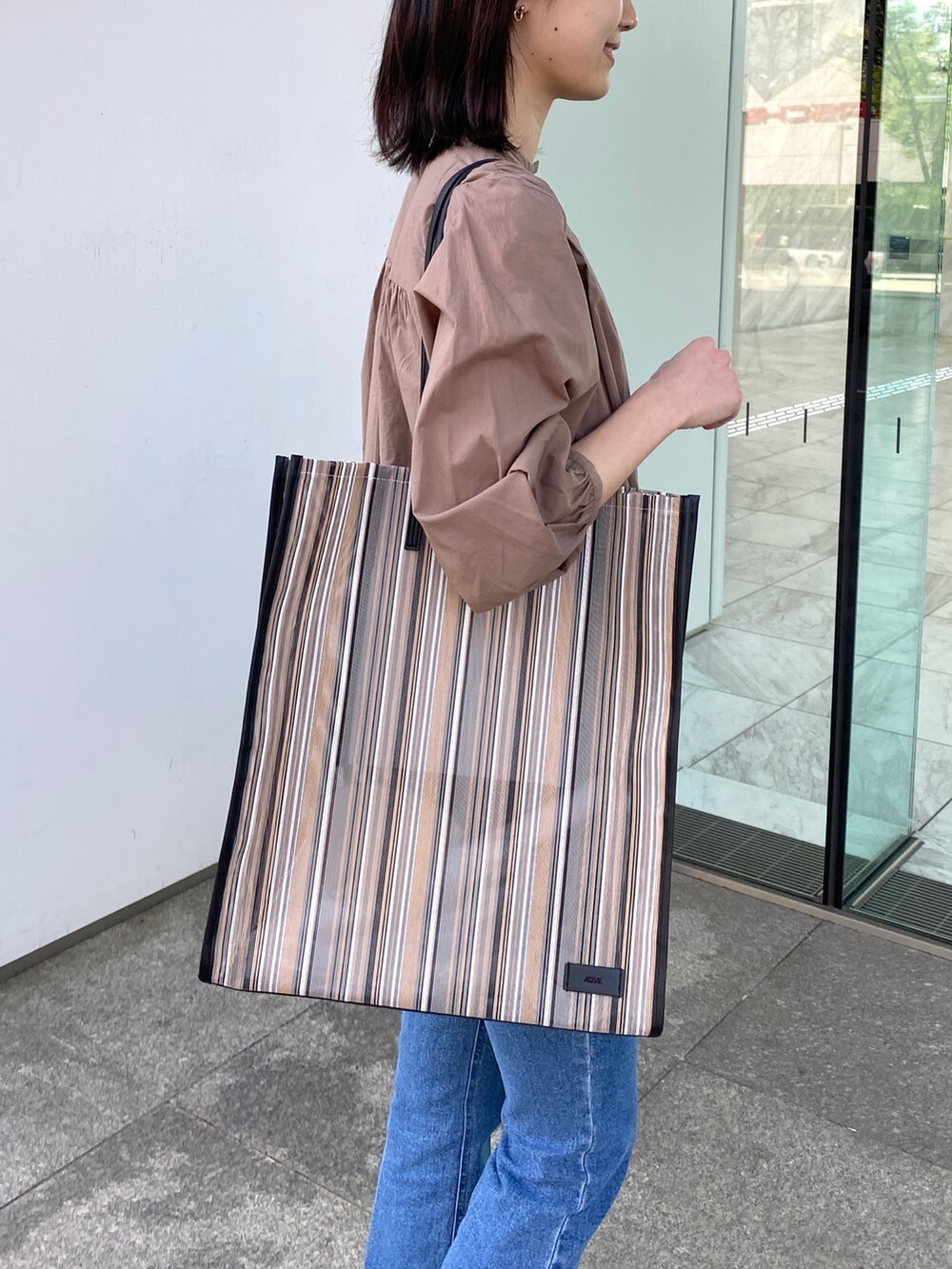 ベージュ系のシャツ/ブラウス、ブラック系のトートバッグ、ブラウン系のサンダルを着用したレディースの春コーディネートの5枚目の写真