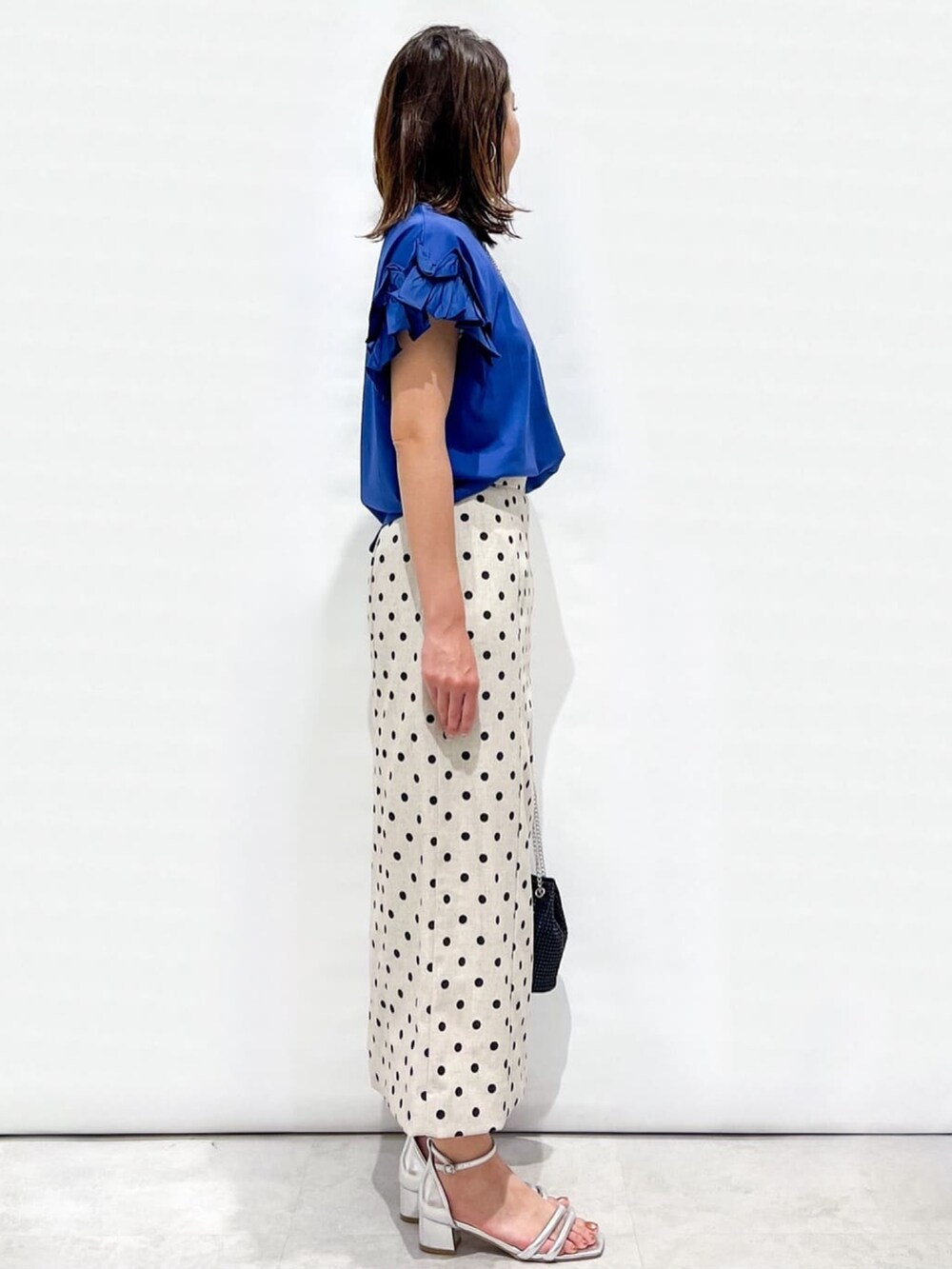 ベージュ系のスカート、ブラック系のショルダーバッグ、シルバー系のサンダルを着用したレディースの夏コーディネートの3枚目の写真