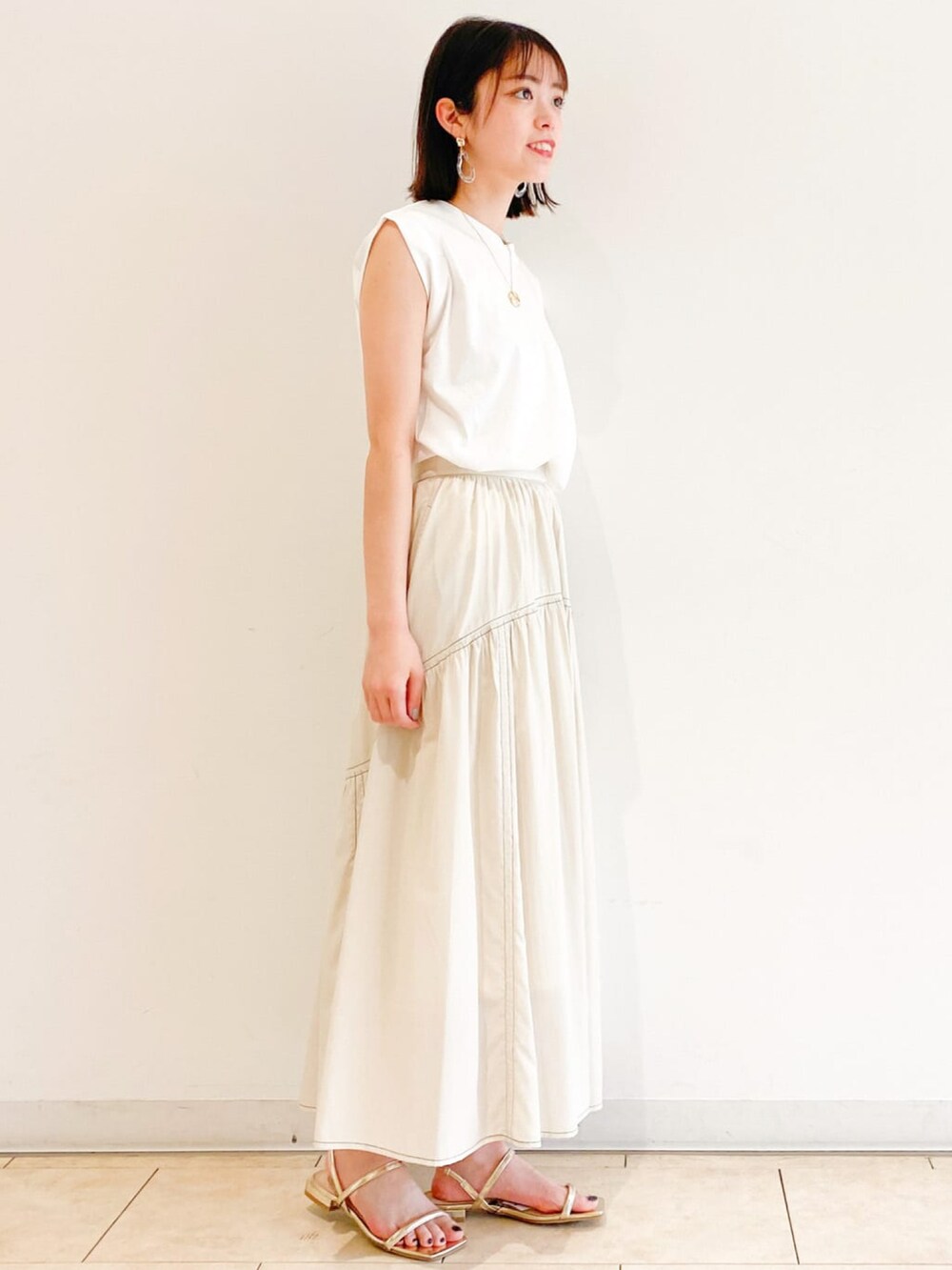 ホワイト系のTシャツ/カットソー、ホワイト系のスカート、ゴールド系のネックレスを着用したレディースの夏コーディネートの2枚目の写真