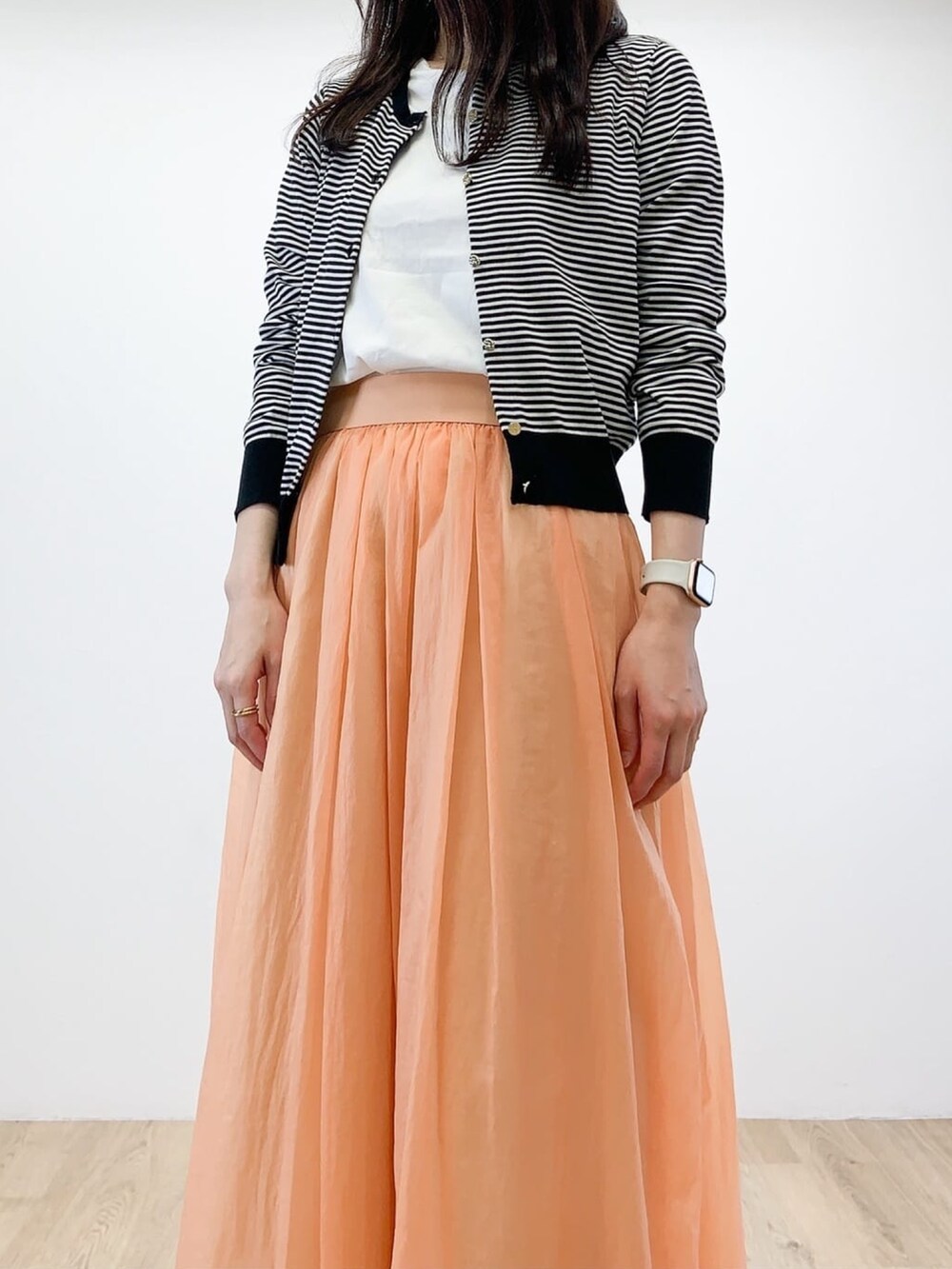 ホワイト系のカーディガン/ボレロ、ホワイト系のTシャツ/カットソー、オレンジ系のスカートを着用したレディースの春コーディネートの4枚目の写真