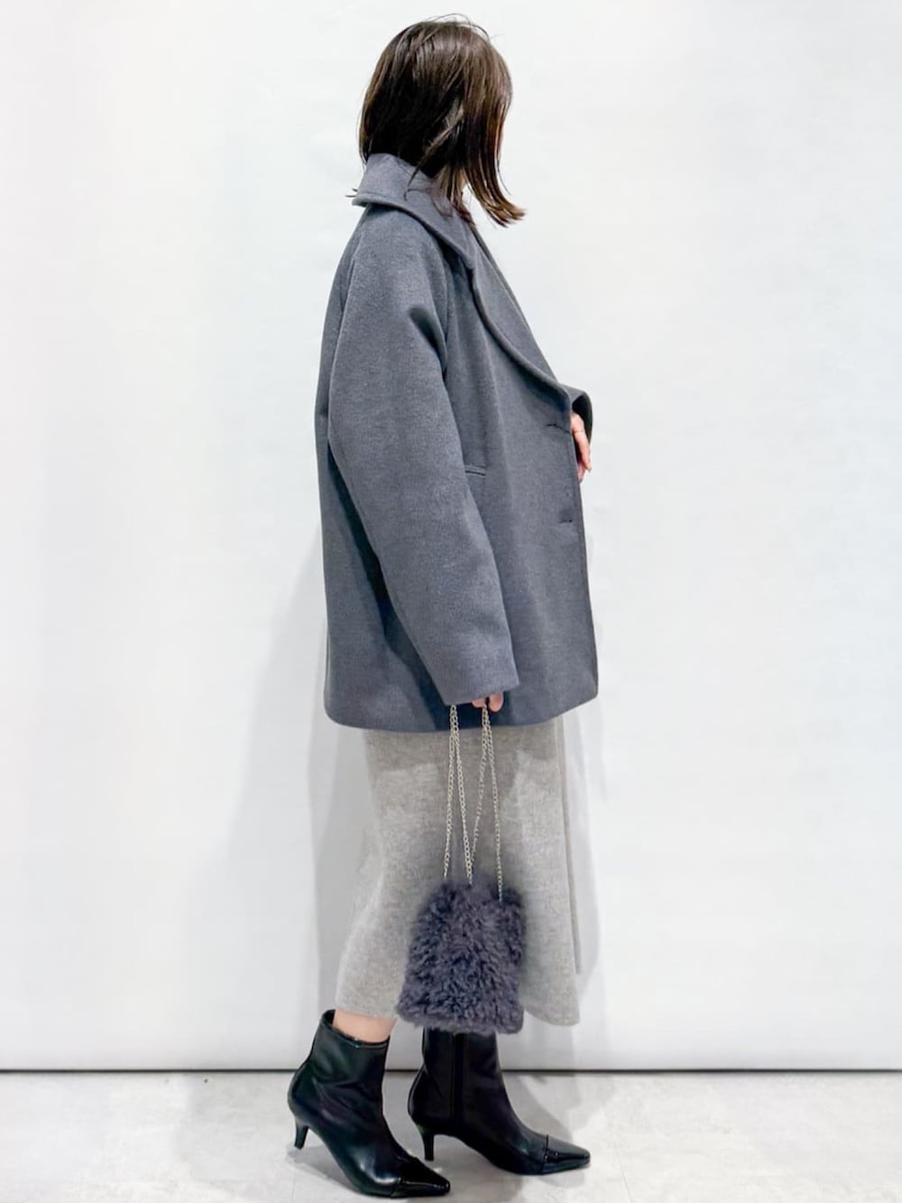 ブラック系のニット/セーター、グレー系のピーコート、グレー系のショルダーバッグを着用したレディースの秋コーディネートの4枚目の写真