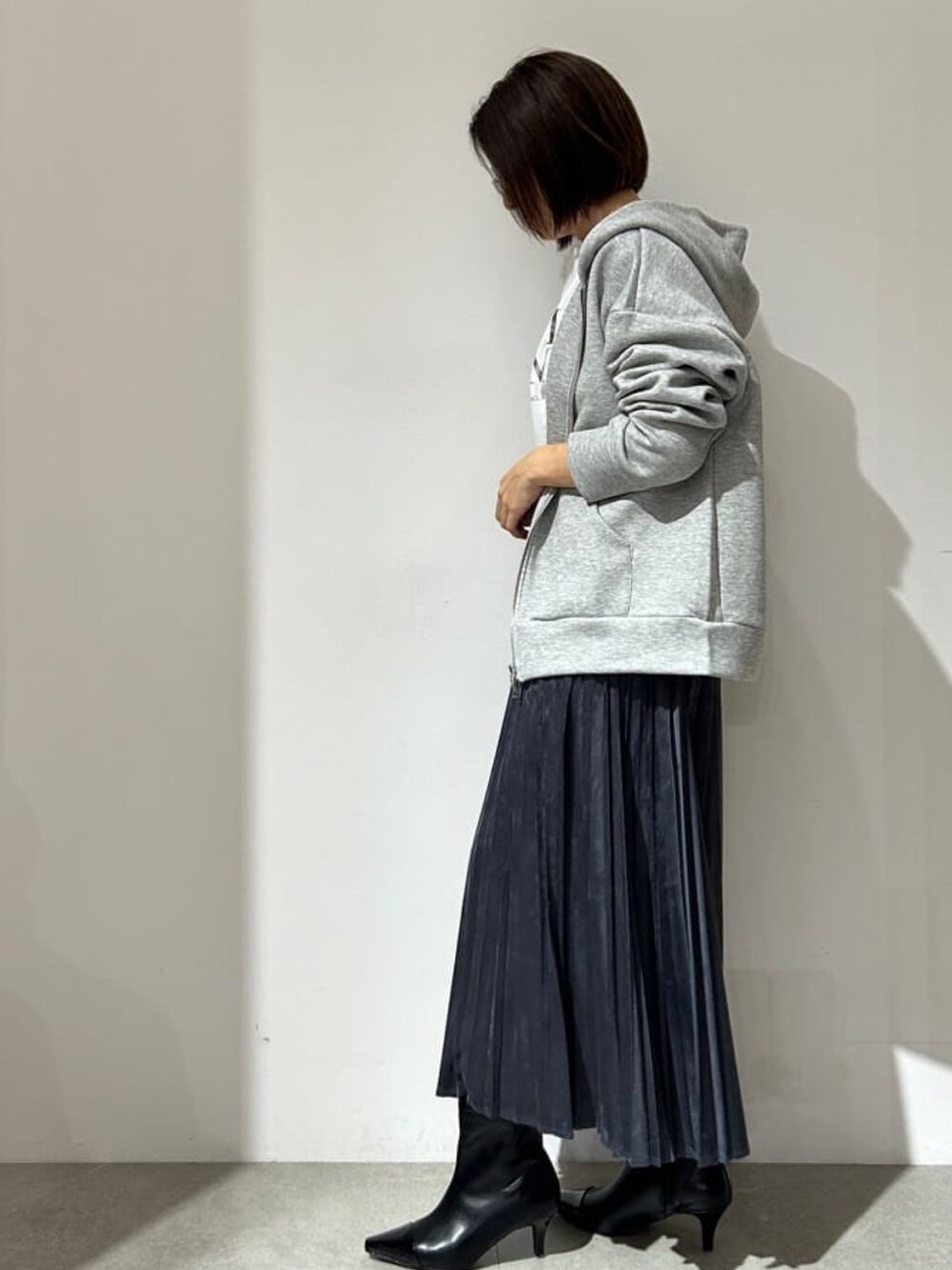 グレー系のスカート、ホワイト系のTシャツ/カットソー、グレー系のパーカーを着用したレディースの秋コーディネートの2枚目の写真