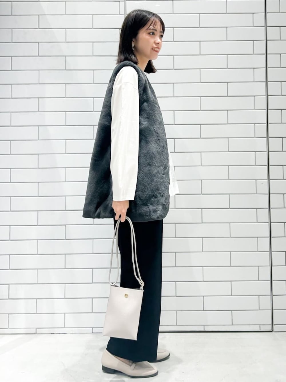 グレー系のパンプス、ブラック系のその他パンツ、グレー系のショルダーバッグを着用したレディースの秋コーディネートの2枚目の写真
