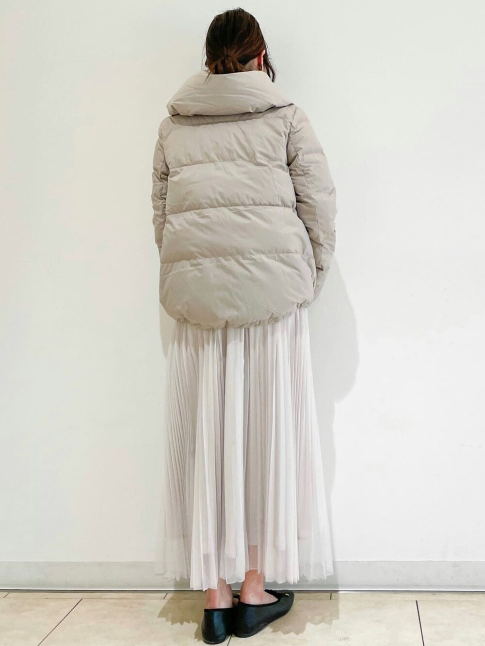 ベージュ系のダウンジャケット/コート、ベージュ系のスカート、ホワイト系のニット/セーターを着用したレディースの冬コーディネートの3枚目の写真