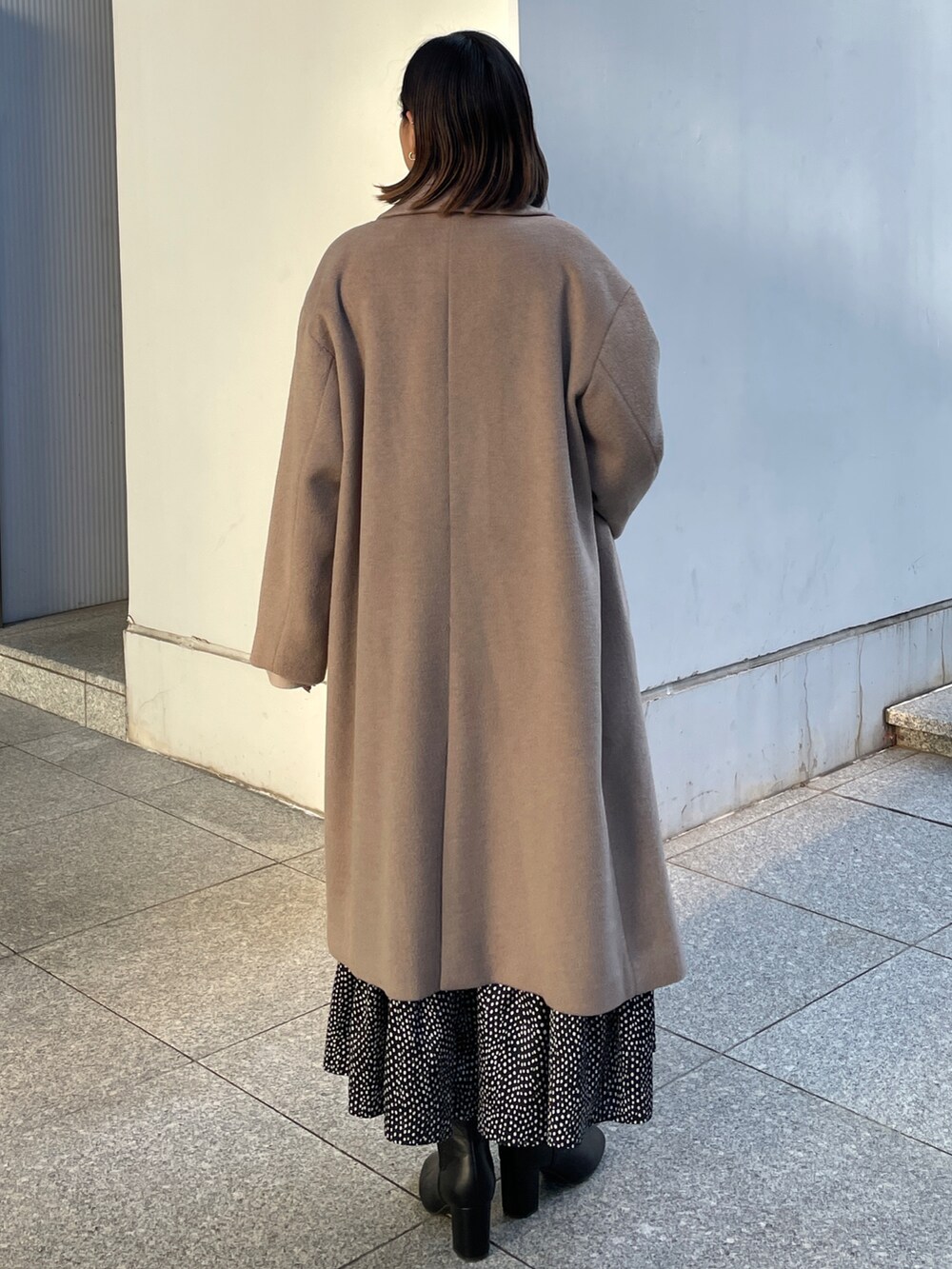 ベージュ系のチェスターコート、ベージュ系のニット/セーター、ブラック系のブーツを着用したレディースの冬コーディネートの3枚目の写真