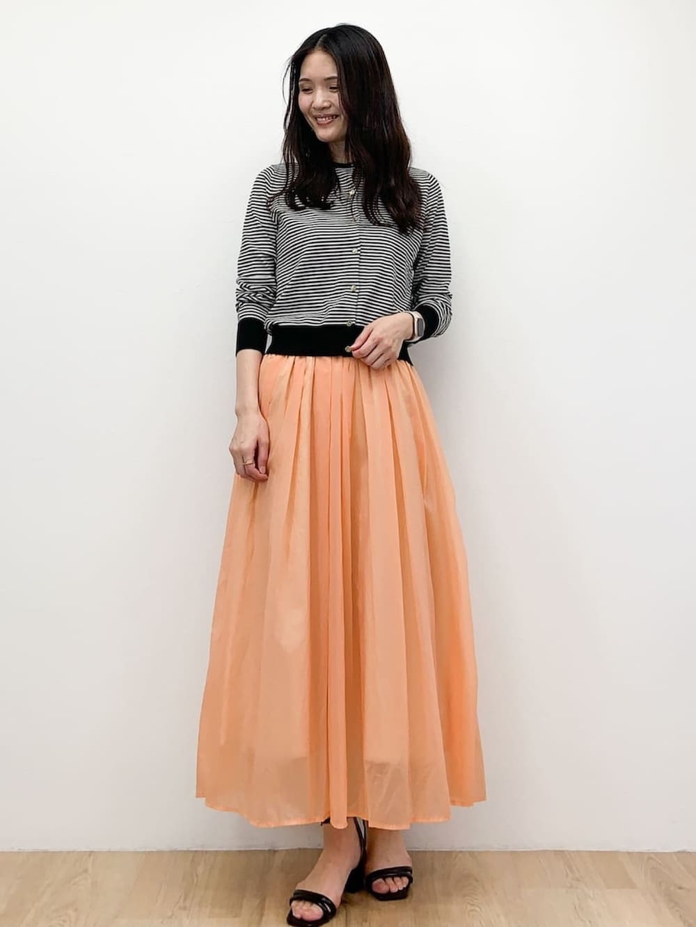 ホワイト系のカーディガン/ボレロ、ホワイト系のTシャツ/カットソー、オレンジ系のスカートを着用したレディースの春コーディネートの2枚目の写真