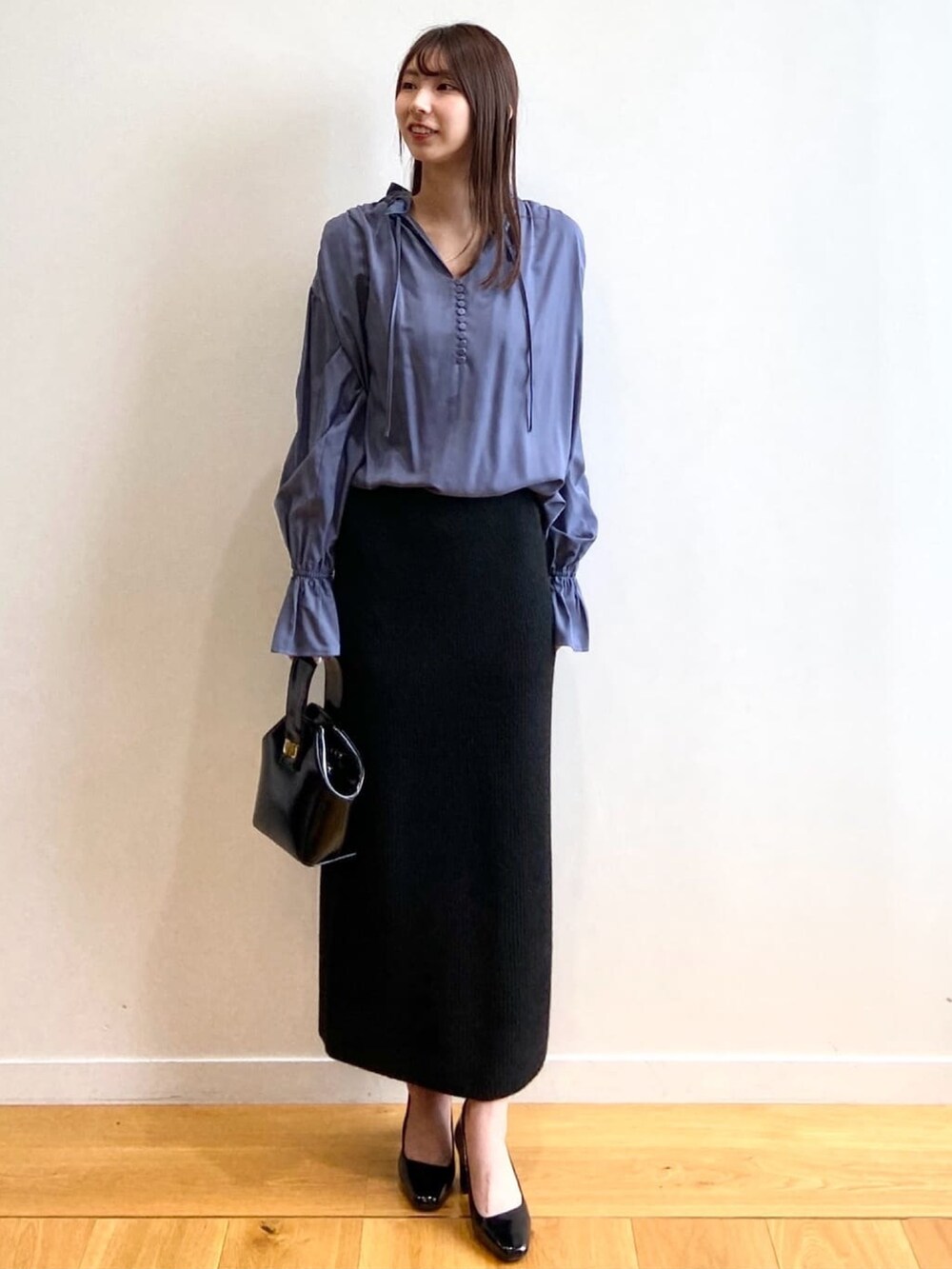 ブラック系のショルダーバッグ、ブルー系のシャツ/ブラウス、ブラック系のパンプスを着用したレディースの秋コーディネートの2枚目の写真