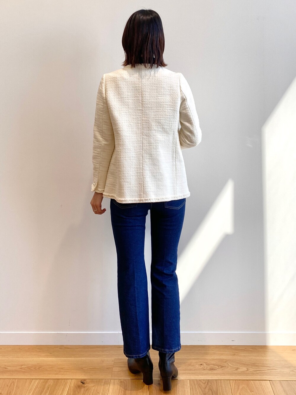 ホワイト系のノーカラージャケット、ブラック系のTシャツ/カットソー、ブラック系のブーツを着用したレディースの冬コーディネートの4枚目の写真