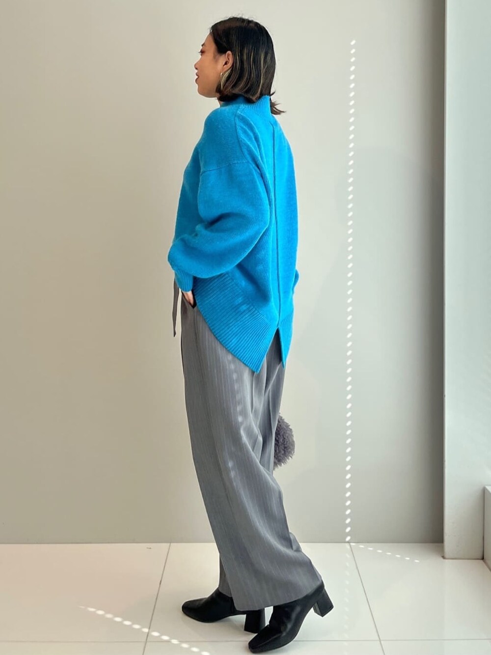 ブルー系のニット/セーター、グレー系のその他パンツ、グレー系のショルダーバッグを着用したレディースの秋コーディネートの2枚目の写真