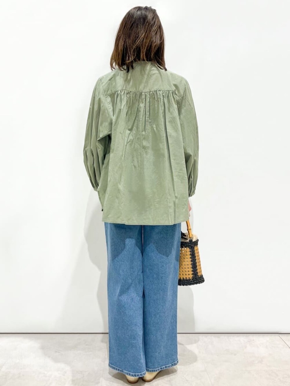 グリーン系のシャツ/ブラウス、ゴールド系のパンプス、ブラック系のトートバッグを着用したレディースの春コーディネートの3枚目の写真