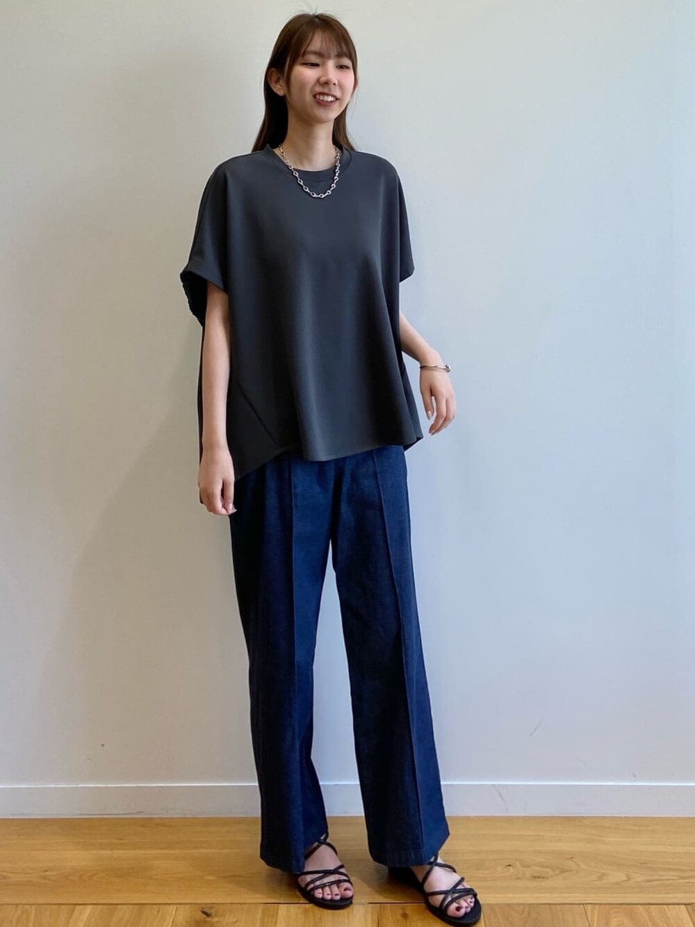 グレー系のTシャツ/カットソー、ブルー系のデニムパンツ、ブラック系のサンダルを着用したレディースの春コーディネートの2枚目の写真