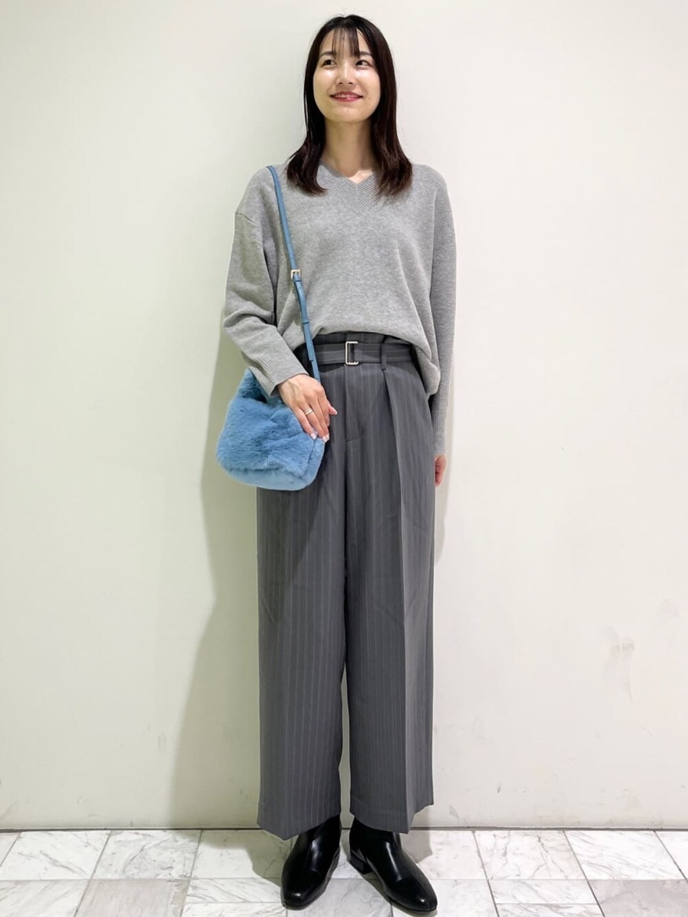 グレー系のニット/セーター、グレー系のその他パンツ、ブルー系のショルダーバッグを着用したレディースの冬コーディネートの2枚目の写真