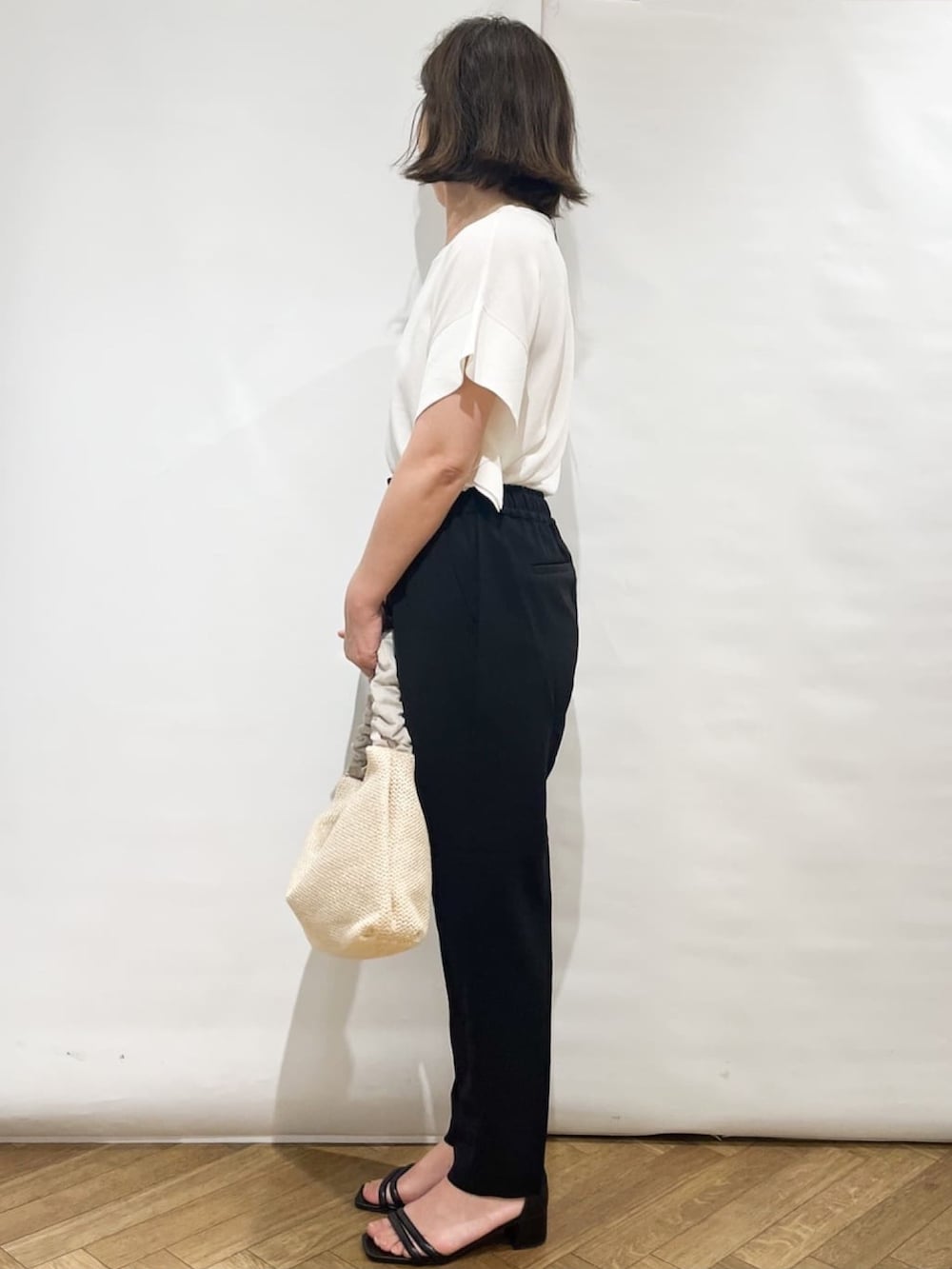 ホワイト系のニット/セーター、ブラック系のその他パンツ、ベージュ系のショルダーバッグを着用したレディースの夏コーディネートの3枚目の写真