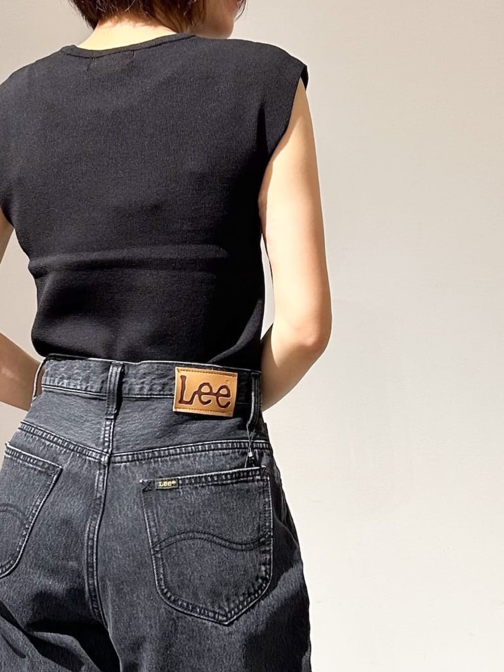 ブラック系のニット/セーター、グレー系のデニムパンツ、シルバー系のパンプスを着用したレディースの夏コーディネートの6枚目の写真