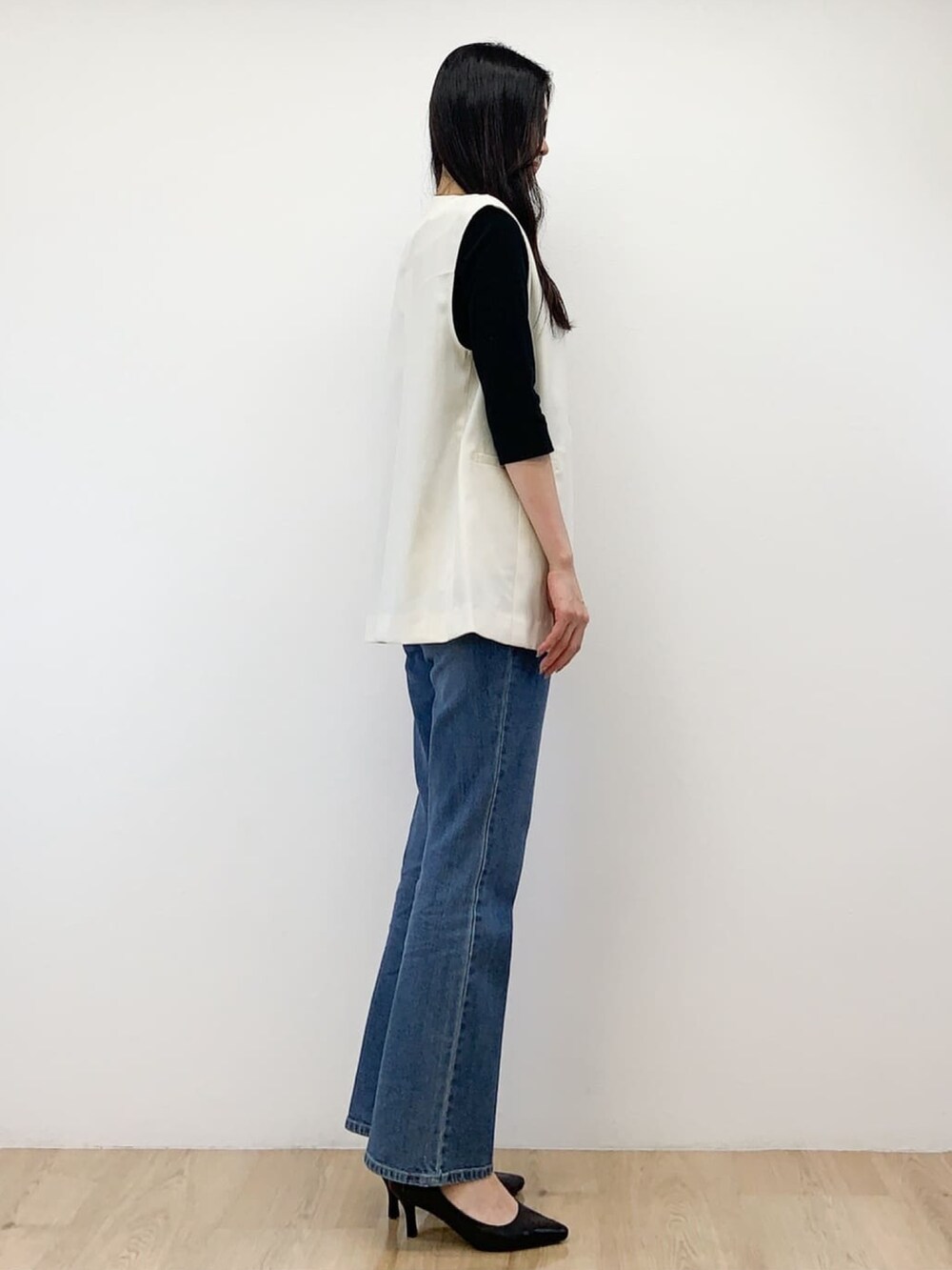 ホワイト系のベスト、ブラック系のTシャツ/カットソー、ブルー系のデニムパンツを着用したレディースの秋コーディネートの4枚目の写真