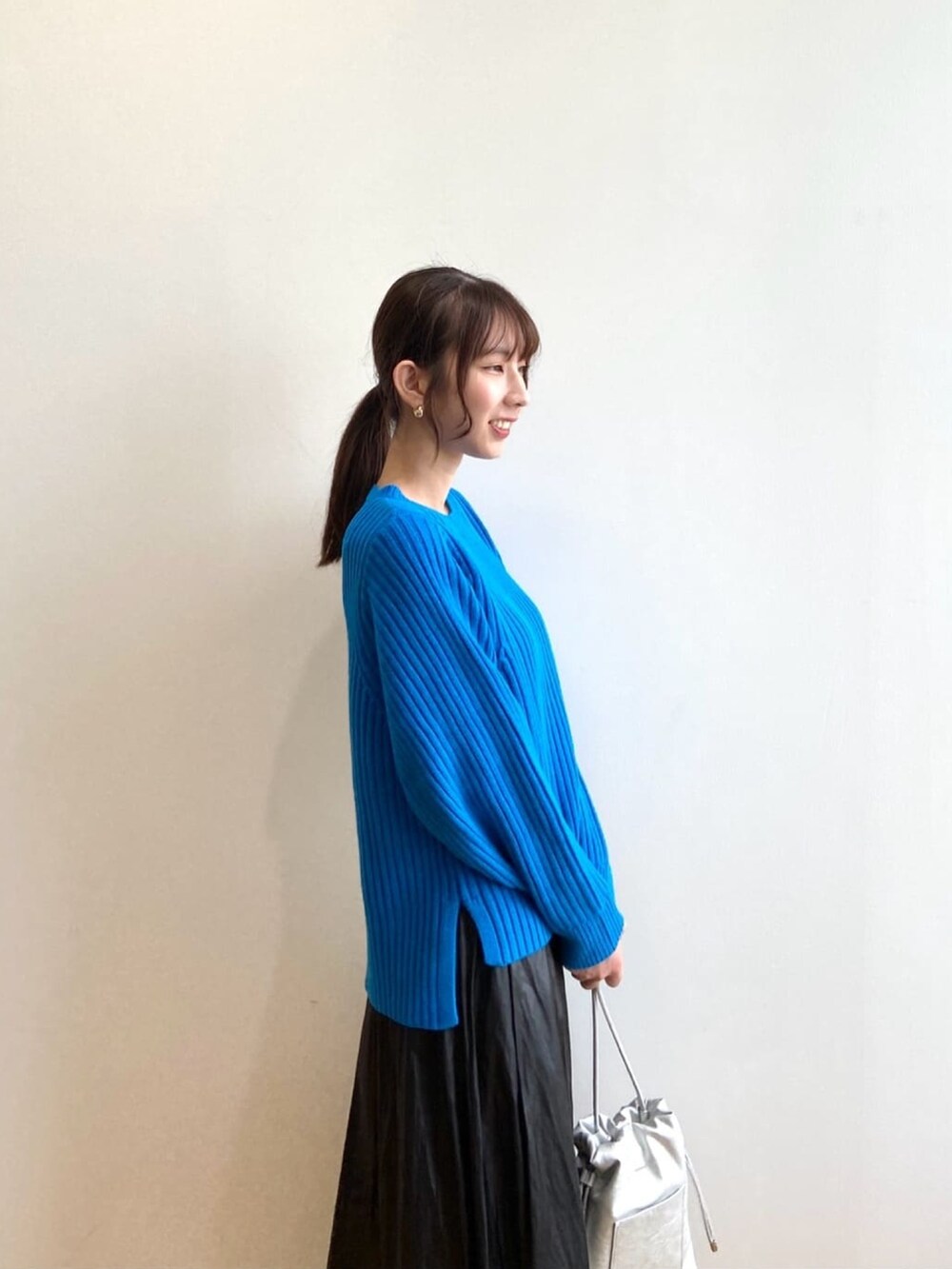 ブルー系のニット/セーター、ブラック系のスカート、ブラック系のブーツを着用したレディースの秋コーディネートの6枚目の写真