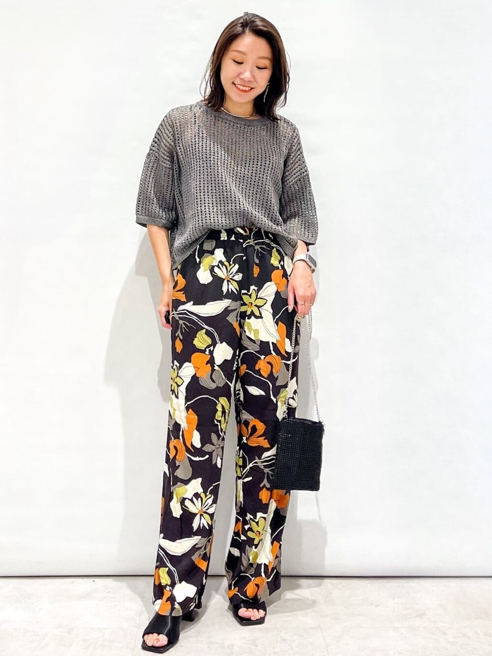 シルバー系のニット/セーター、ブラウン系のその他パンツ、ブラック系のショルダーバッグを着用したレディースの夏コーディネートの2枚目の写真