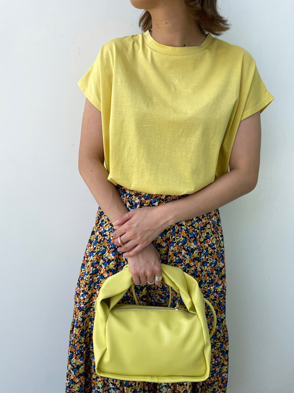 イエロー系のTシャツ/カットソー、オレンジ系のスカート、ホワイト系のパンプスを着用したレディースの夏コーディネートの4枚目の写真