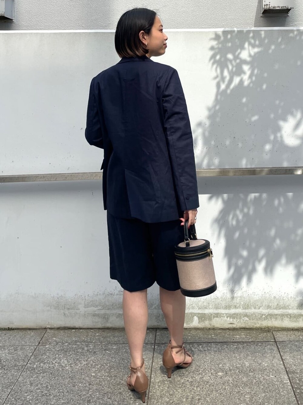 ブルー系のテーラードジャケット、ホワイト系のTシャツ/カットソー、ブラウン系のサンダルを着用したレディースの春コーディネートの3枚目の写真