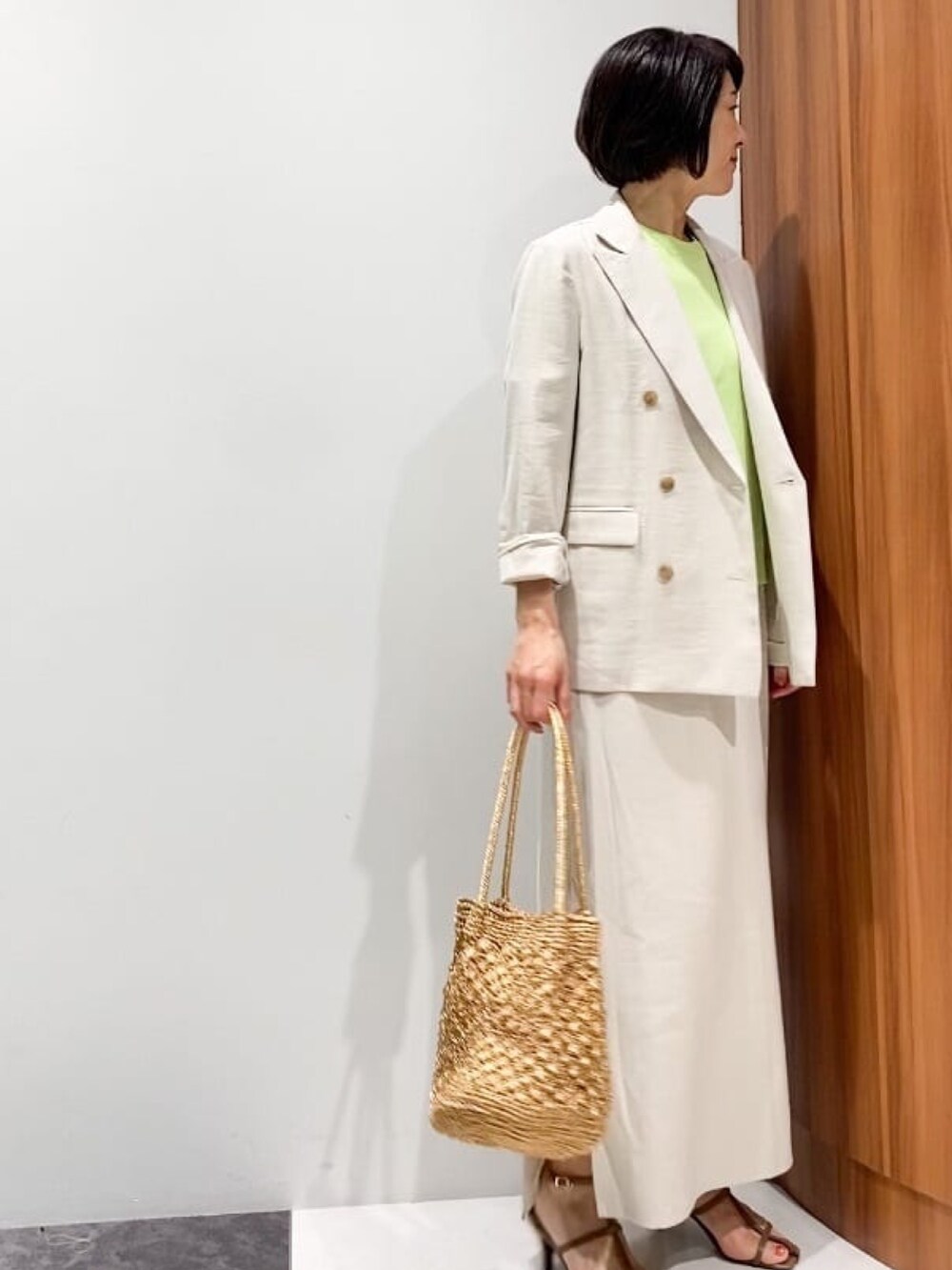 ベージュ系のテーラードジャケット、ベージュ系のスカート、ブラウン系のサンダルを着用したレディースの春コーディネートの4枚目の写真