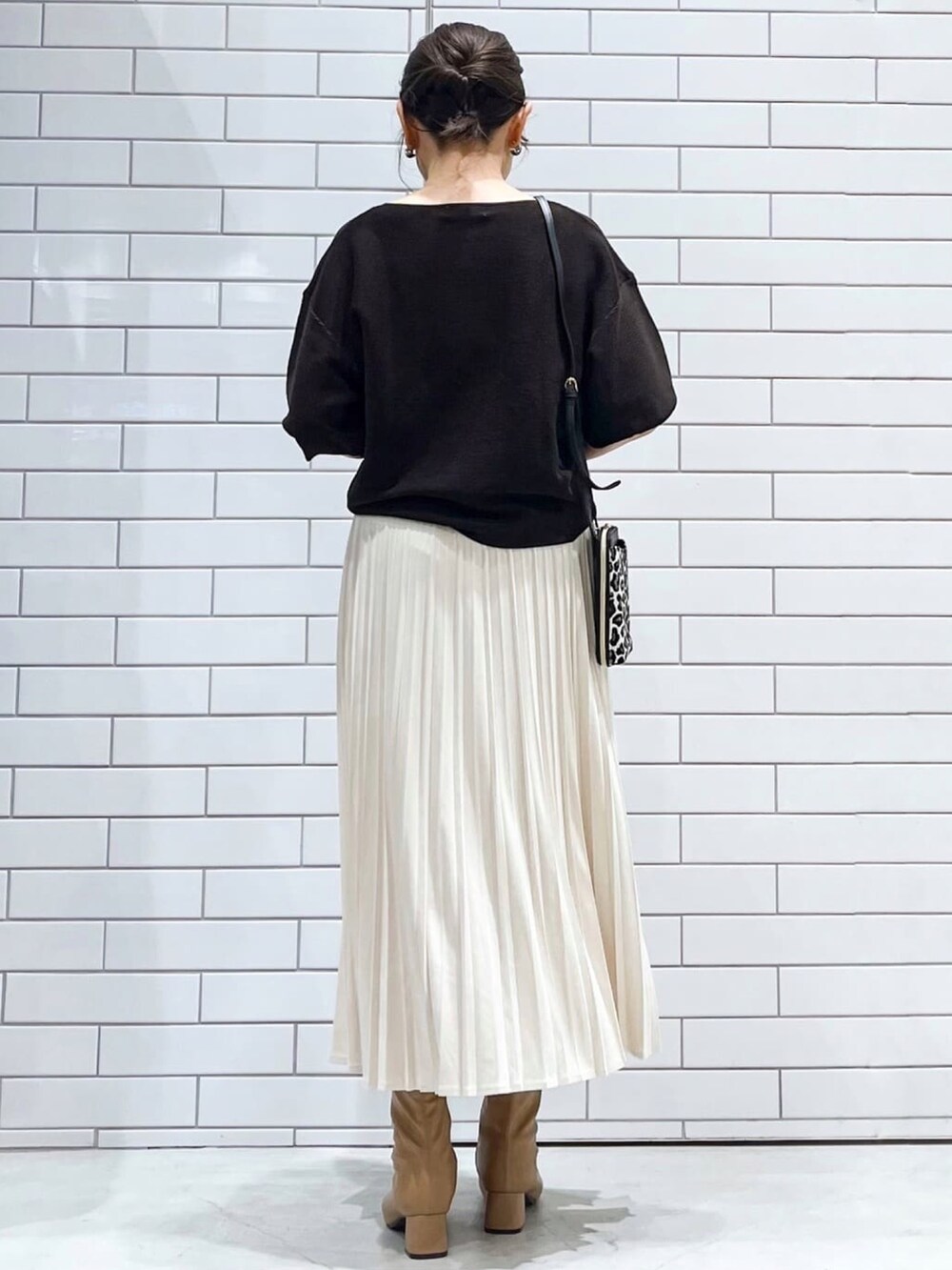 ブラウン系のニット/セーター、ホワイト系のスカート、ブラック系のショルダーバッグを着用したレディースの秋コーディネートの3枚目の写真