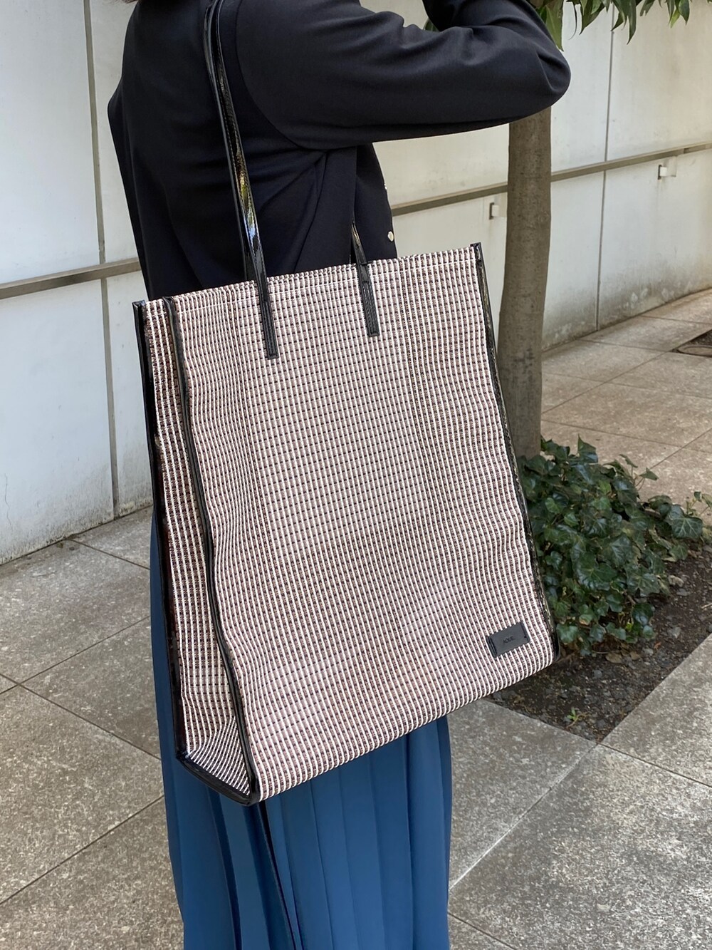 ブルー系のスカート、ブラウン系のサンダル、ブラック系のトートバッグを着用したレディースの春コーディネートの7枚目の写真